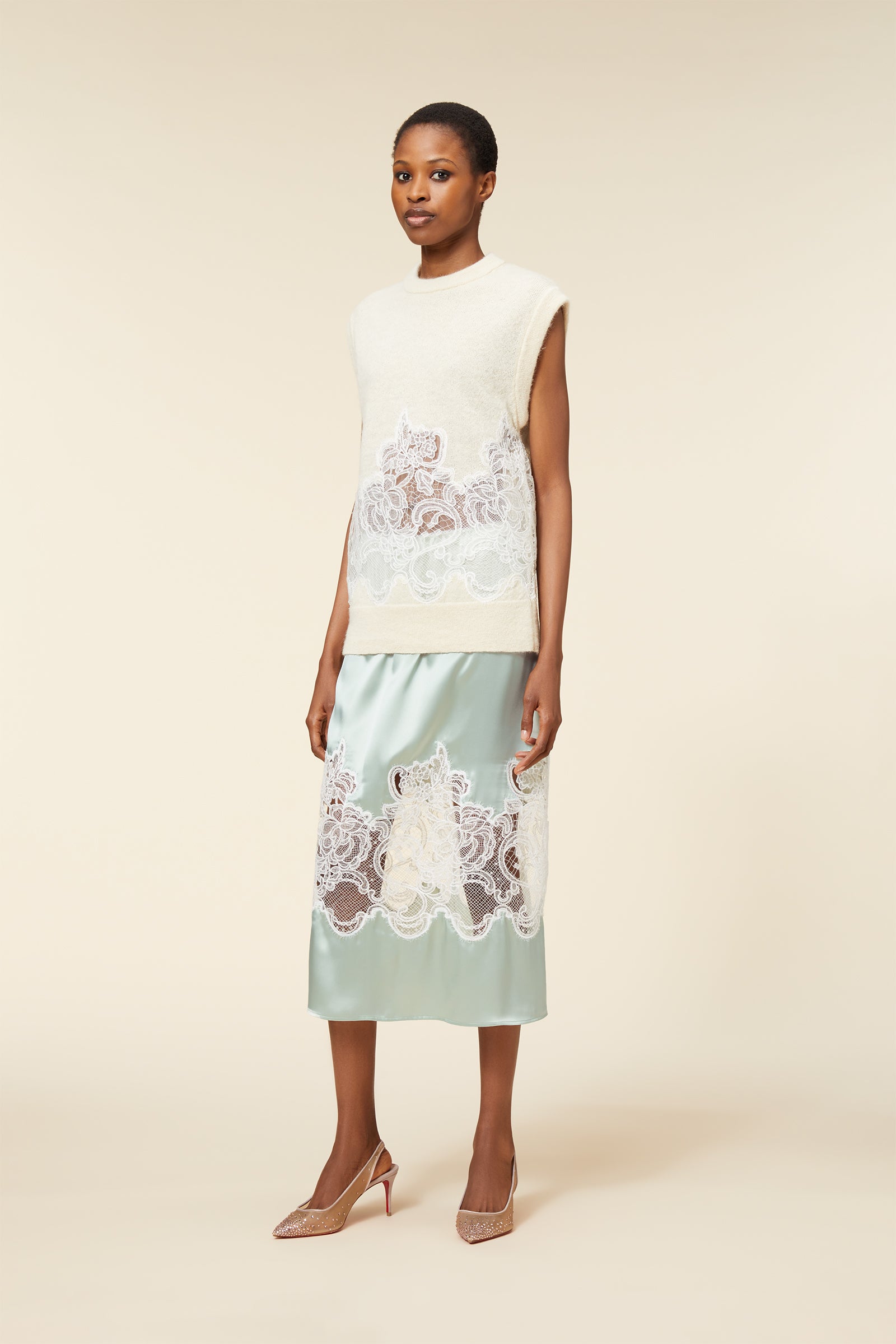 Elegant sleeveless cream top with intricate lace overlay paired with a mint green satin skirt, featuring floral lace details.