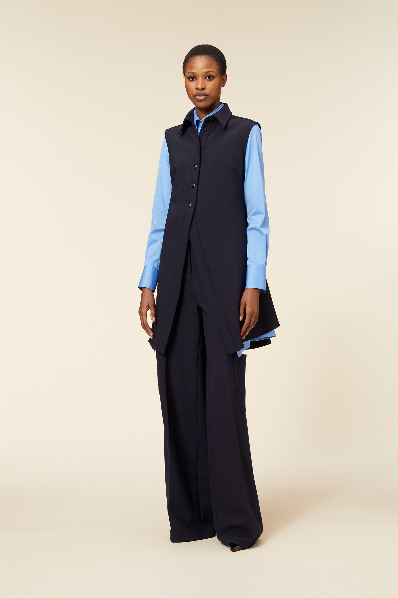 Sleeveless navy vest over light blue shirt paired with matching wide-leg trousers, creating a sleek, modern formal look.