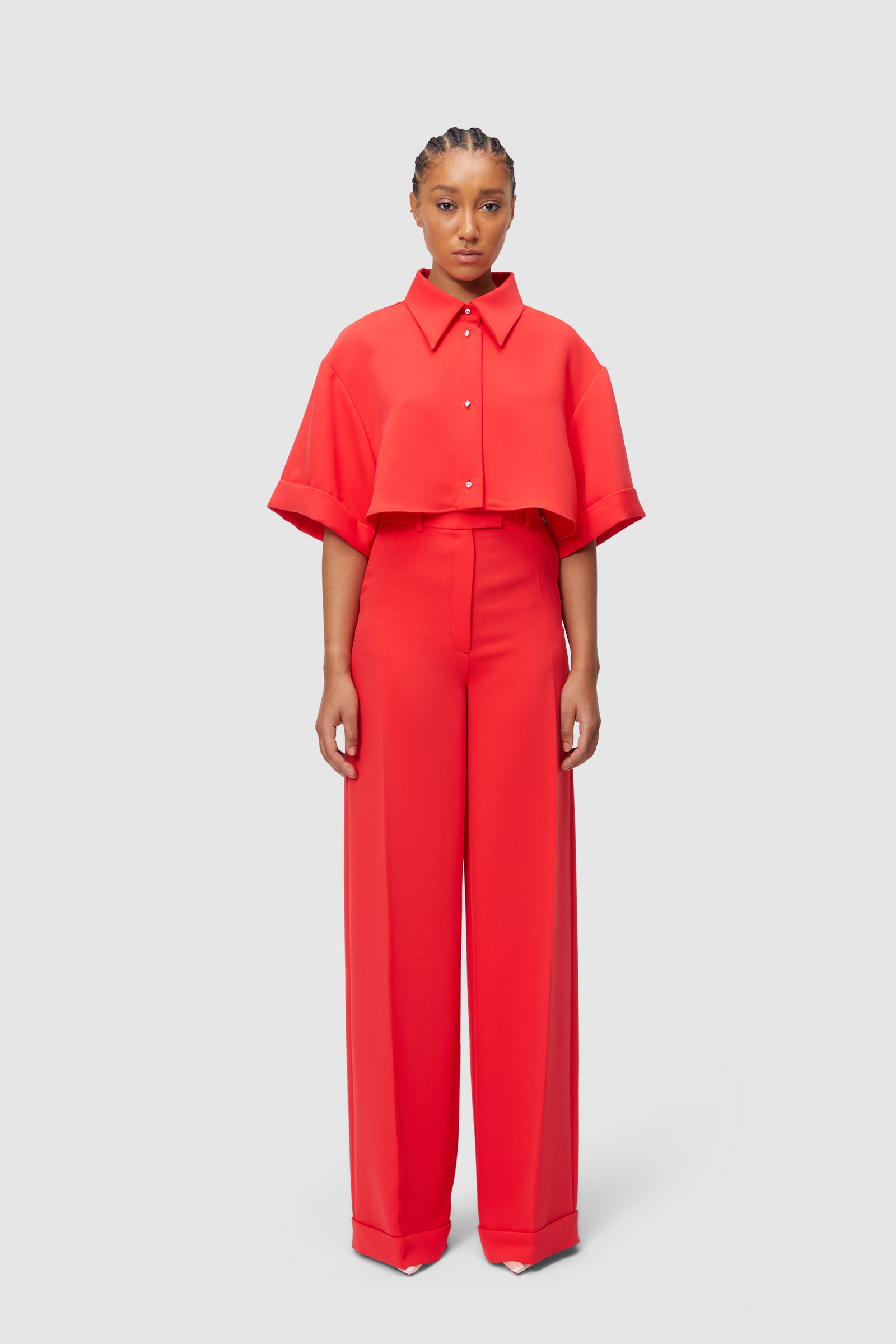 A vibrant red ensemble featuring a cropped short-sleeved top with wide-leg high-waisted trousers, showcasing minimalist elegance.