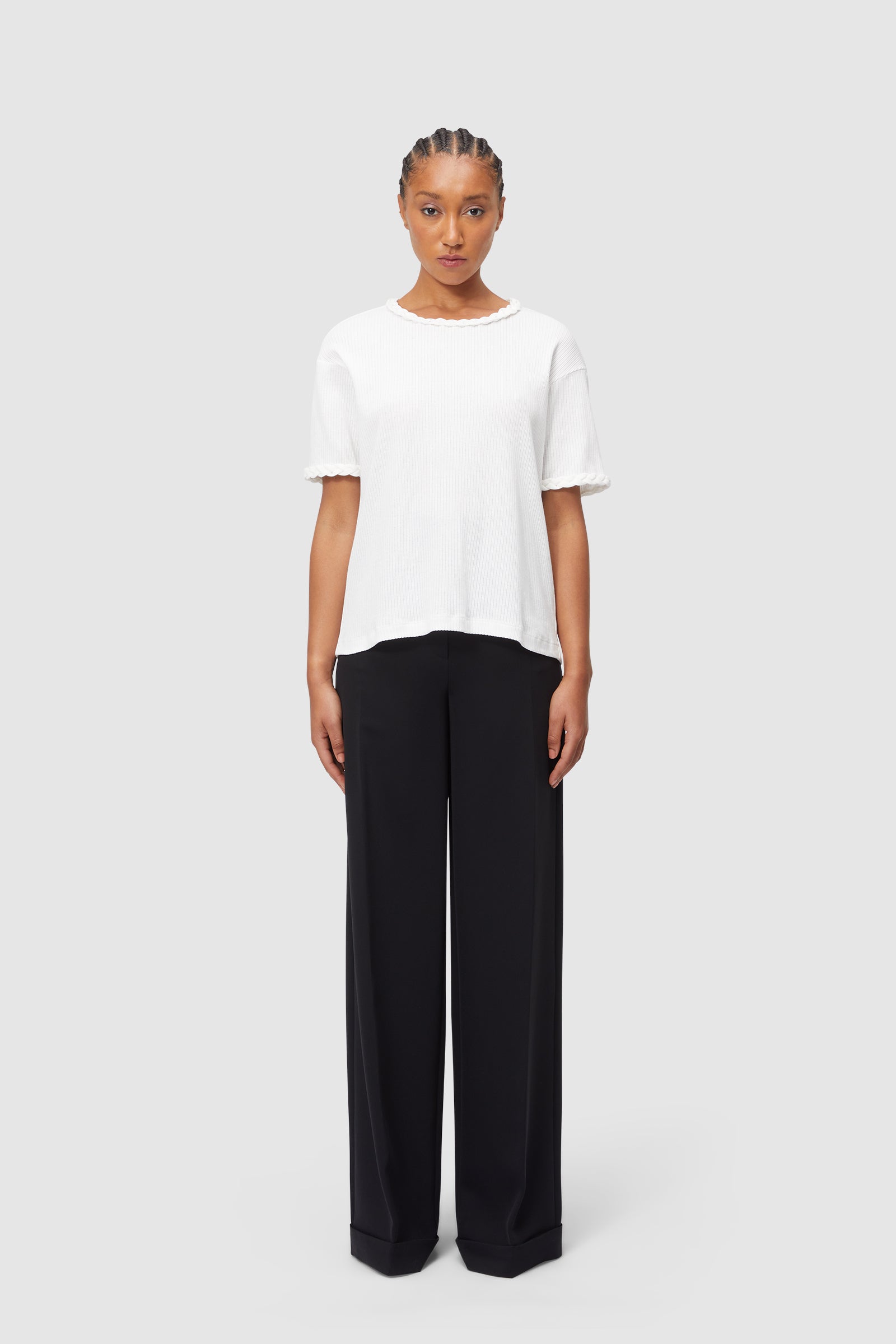 Elegant ensemble of classic black wide-leg trousers paired with a textured white short-sleeve top for a minimalist look.