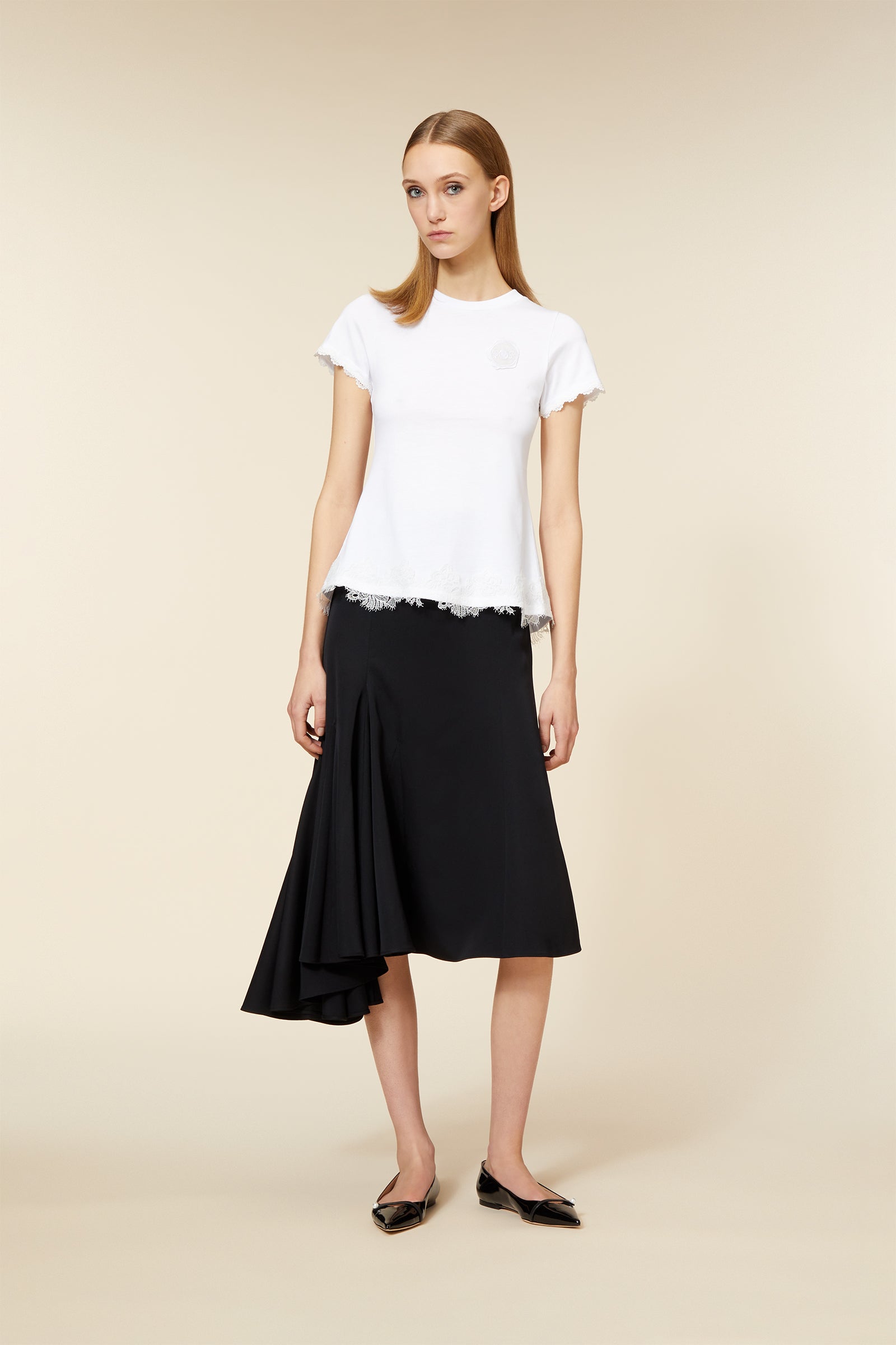 A-line black skirt with asymmetrical hem paired with a short-sleeve white top featuring delicate lace trim accents.