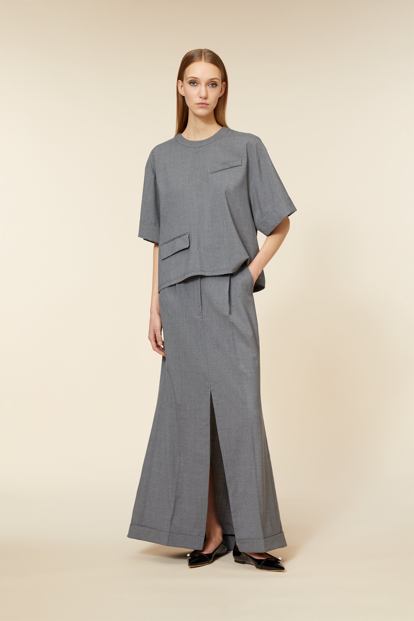 Minimalist gray ensemble featuring a loose top with pocket details and flowing high-waist skirt with front slit.