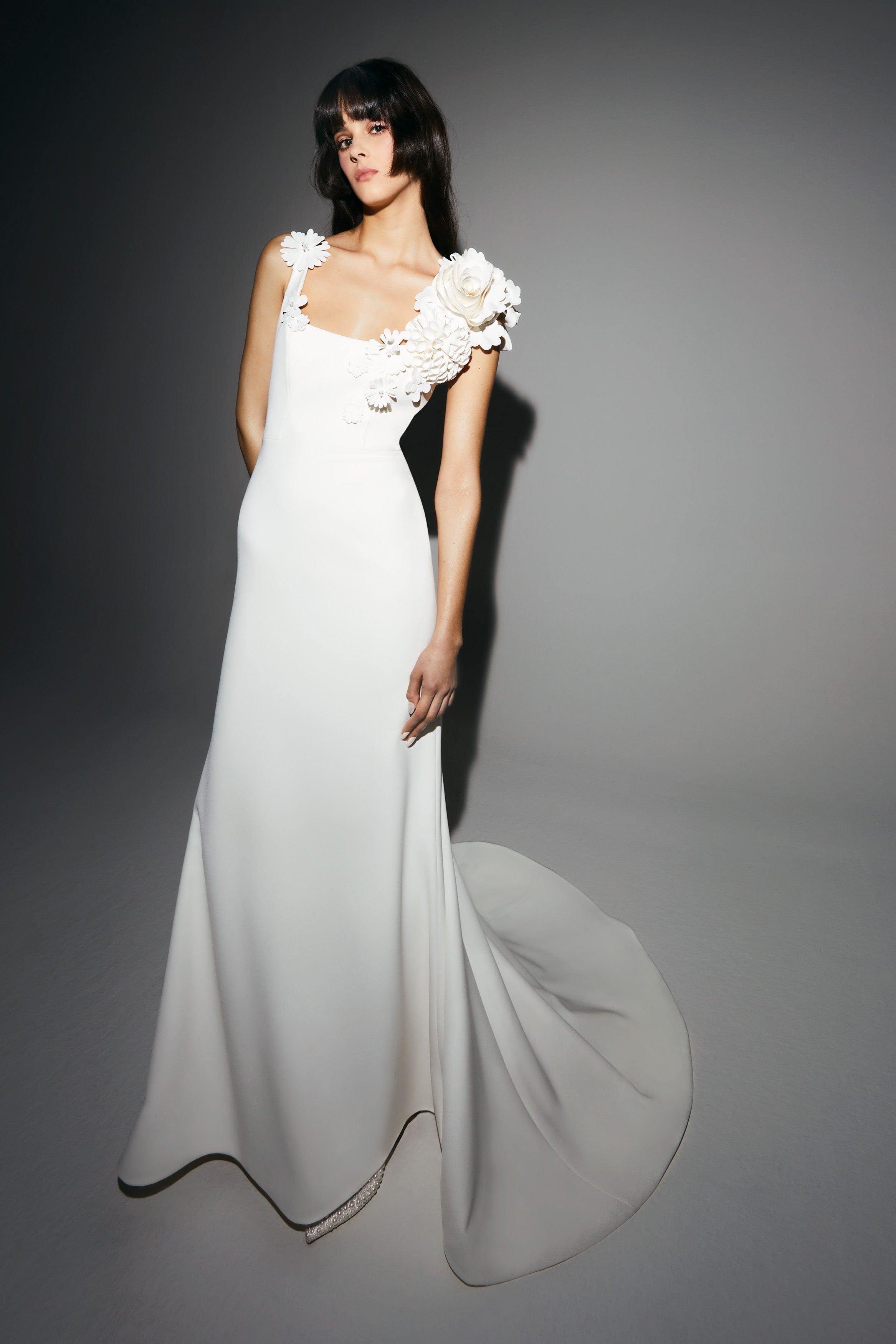 Elegant mermaid gown adorned with mikado ‘abundance fantaisie’ flower embellishments edged asymmetrically around the squared neckline which turns into a plunging v back to create back interest