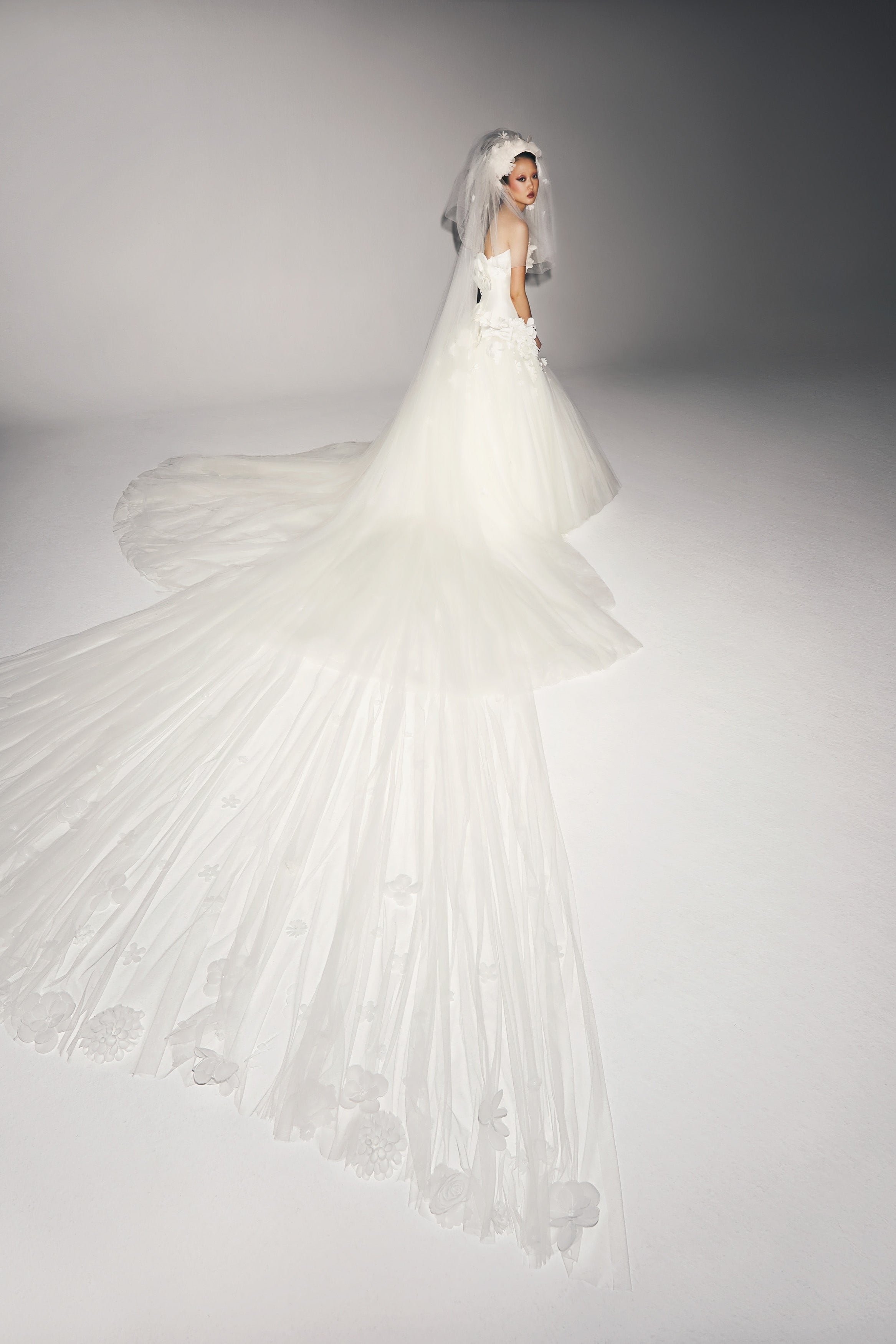 Dramatic tiered tulle veil adorned with sheer organza flowers that lead way to the lavish length of the veil