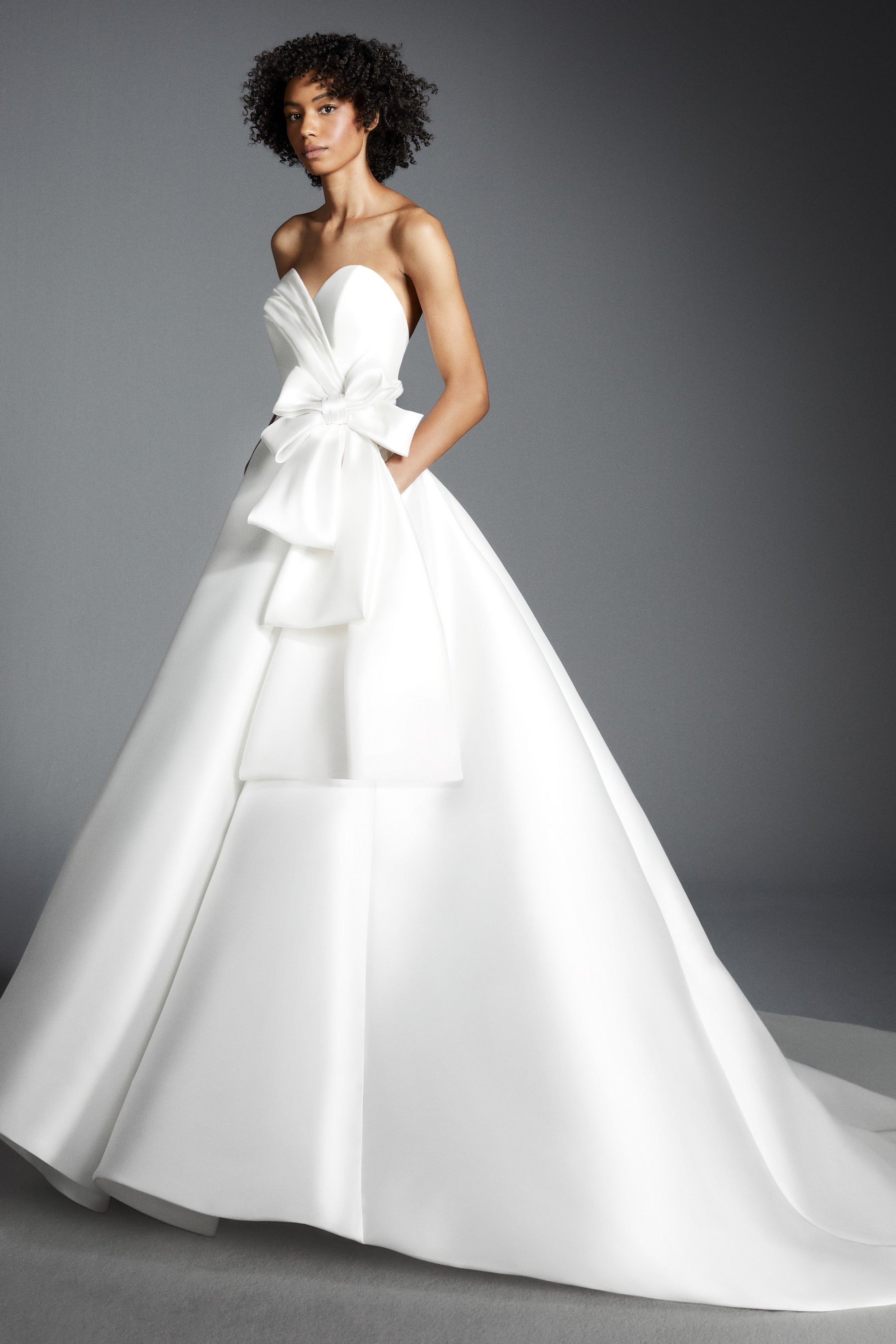 Crafted out of mikado, this gown features an intricately draped sweetheart bodice that leads way to a royal ribbon bow