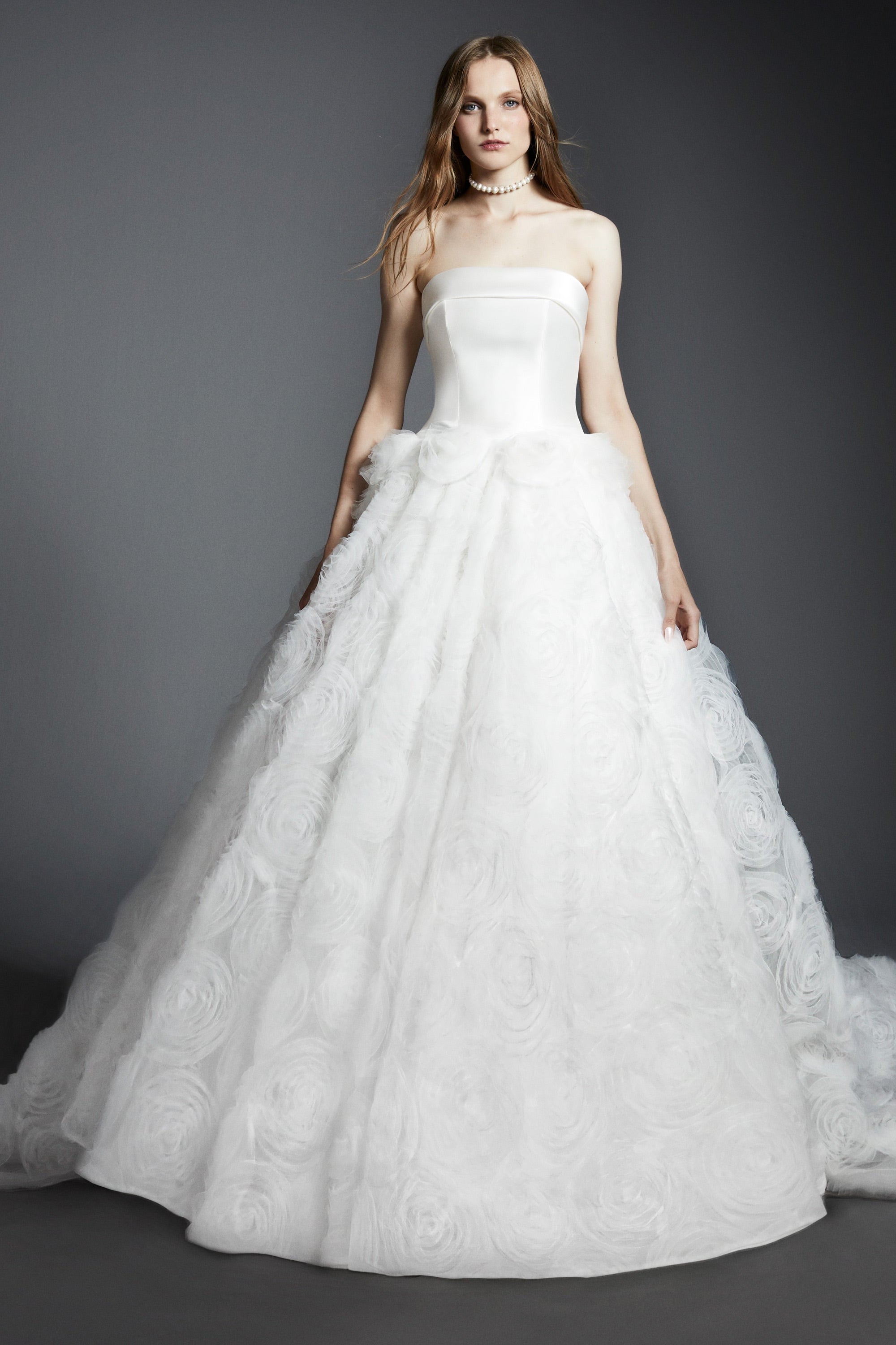 An elegant strapless ballgown featuring a mikado bodice paired with a tulle skirt adorned with textural tulle roses