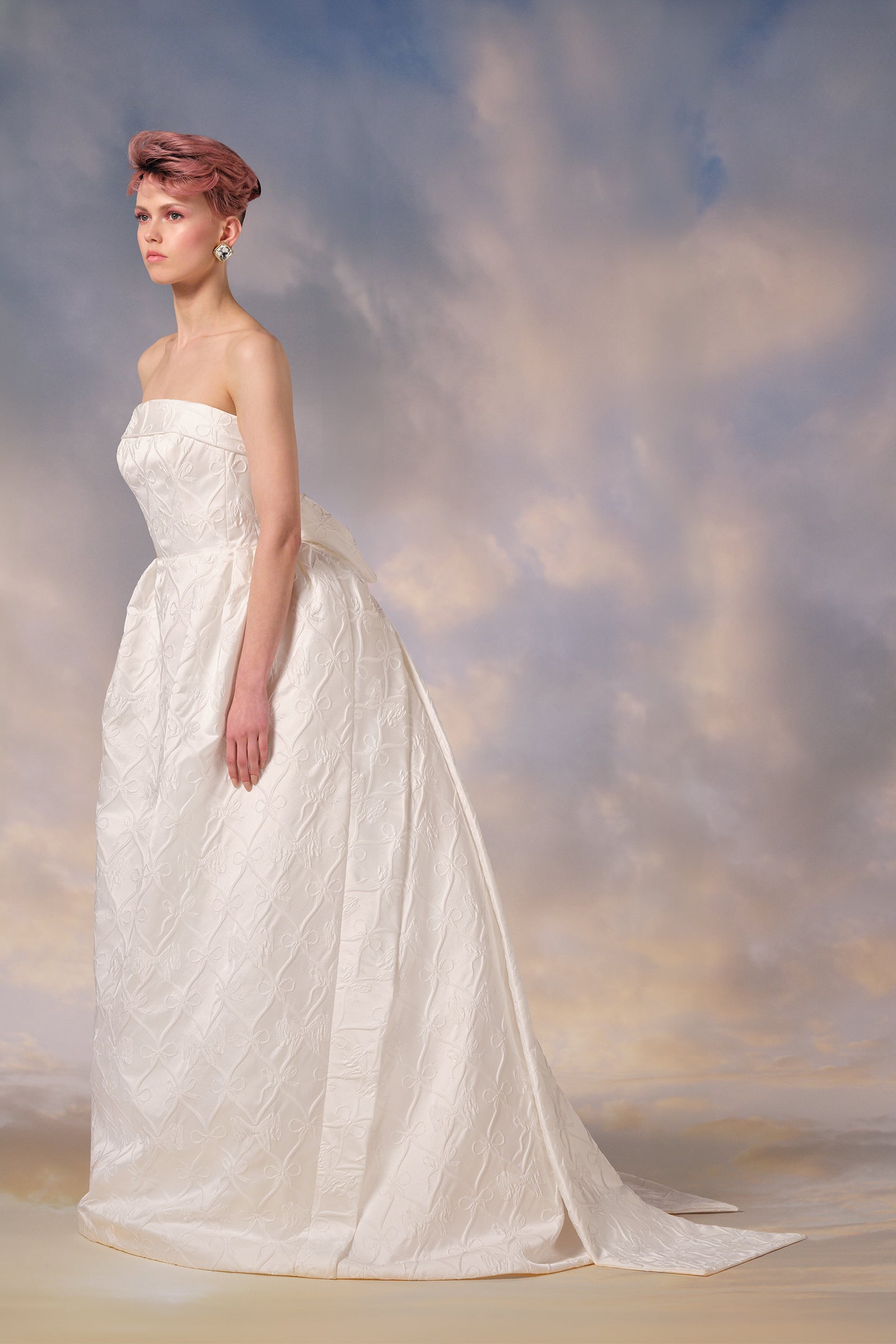 Crafted in our ecxlusive custom bow jacquard, this gown features a sculpted bell-shaped skirt that elegantly wraps over a regent puffed back skirt, from the Viktor&Rolf Mariage collection.