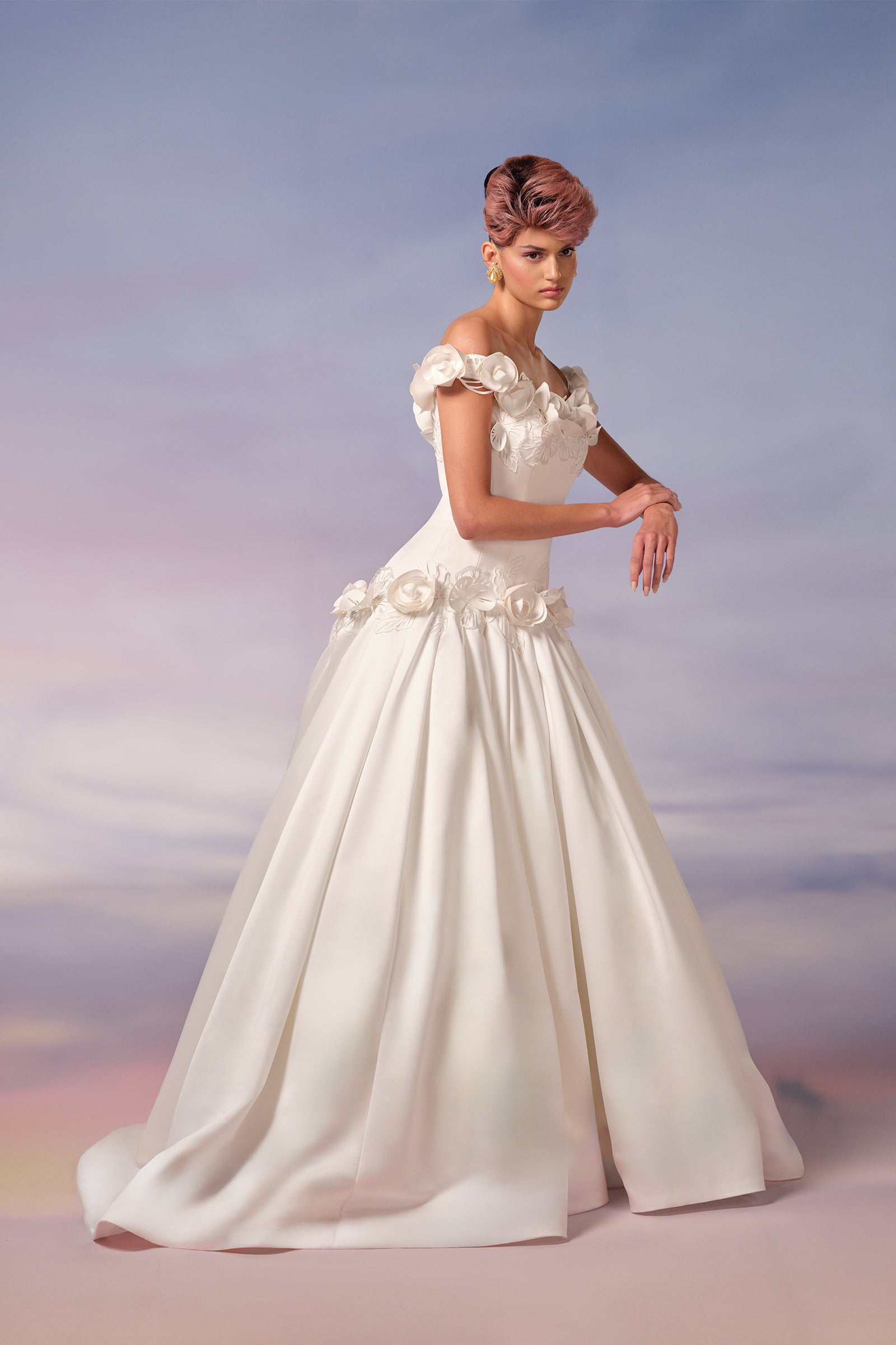 This breathtaking bonded satin gown is embellished with delicately handcrafted lace pansies, featuring intricate cut-out details and sculpted blossoms with shimmering embroidered petals and foliage, adorning the off-shoulder neckline and dropped waist, from the Viktor&Rolf Mariage collection.