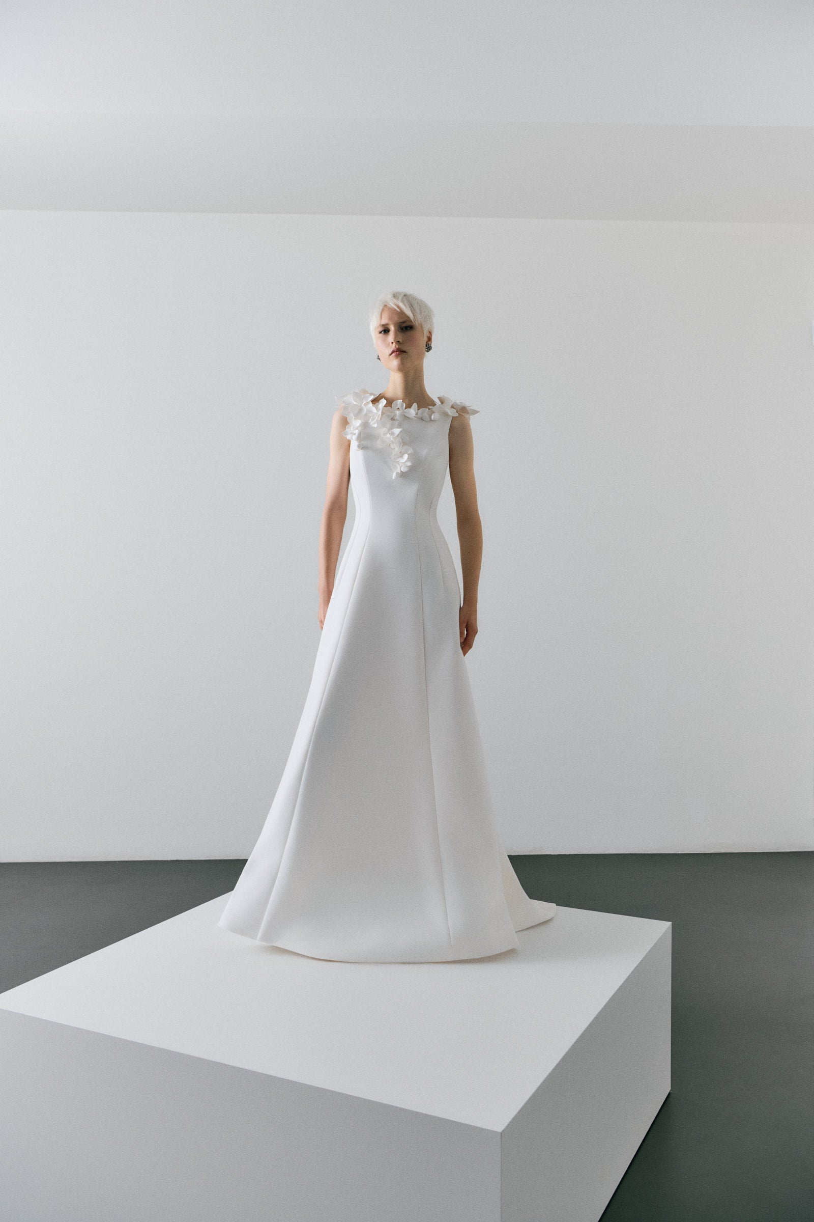 White wedding dress on a mannequin against a plain background