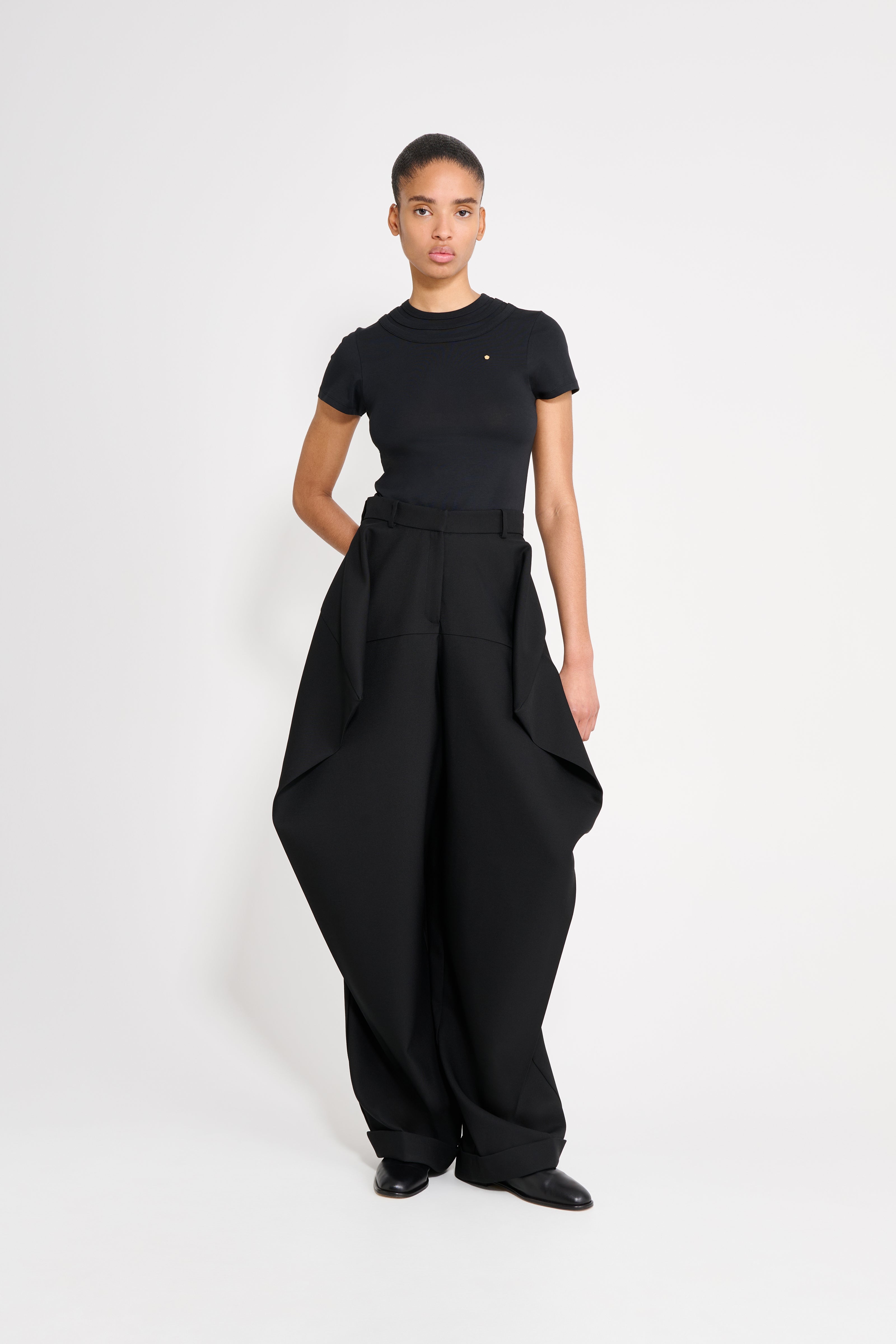 Person wearing a black outfit with wide-leg pants on a white background