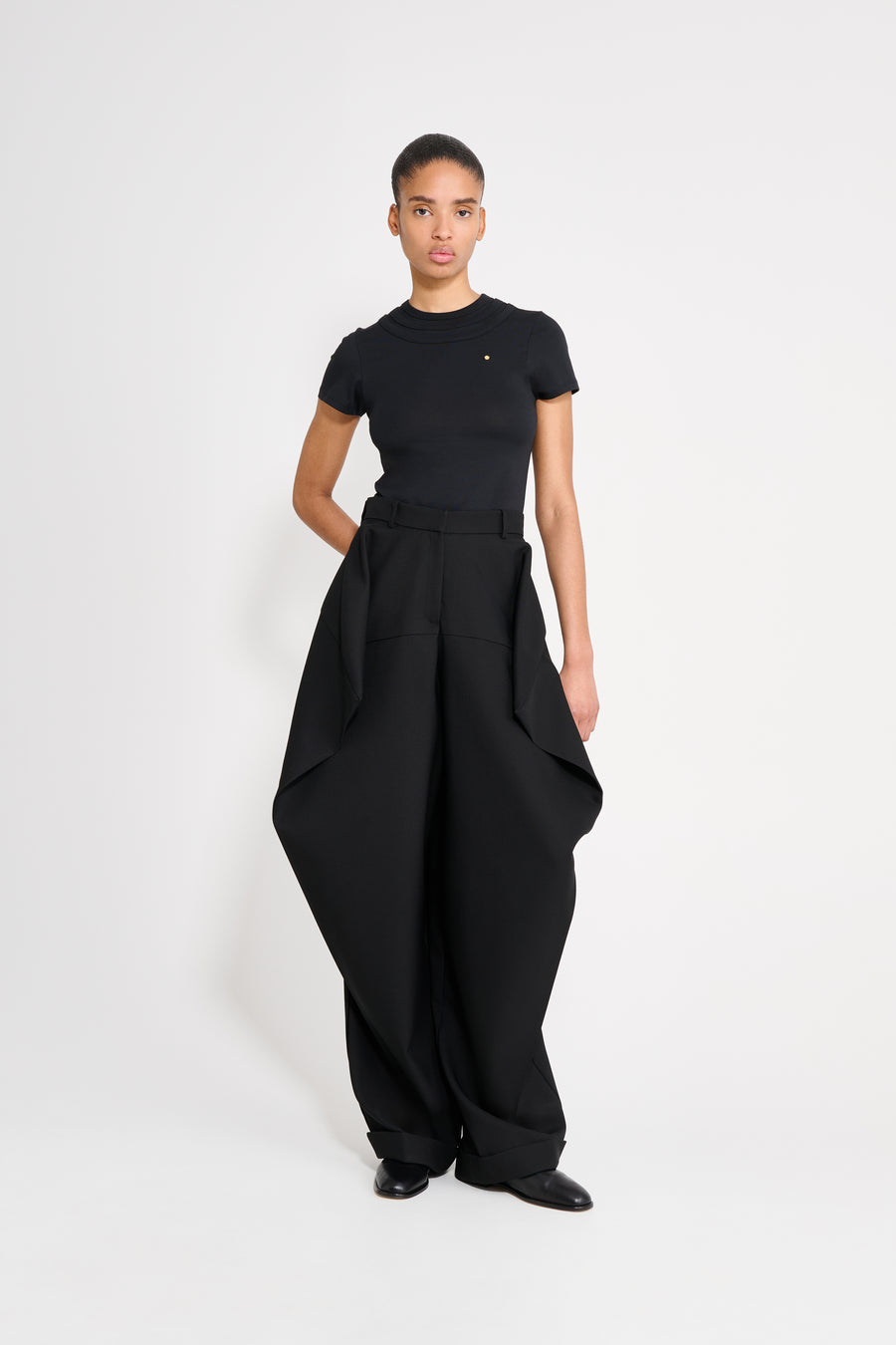 Person wearing a black outfit with wide-leg pants on a white background
