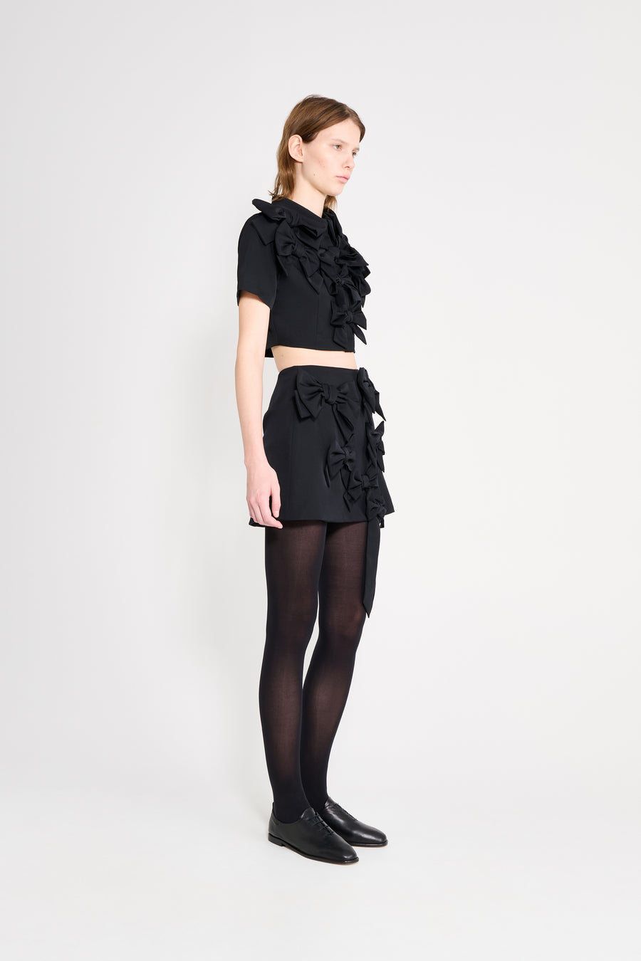 The wool skirt features the seasonal bow bouquet technique, where timeless elegance meets refined craftsmanship in a seamless fusion of sophistication and grace