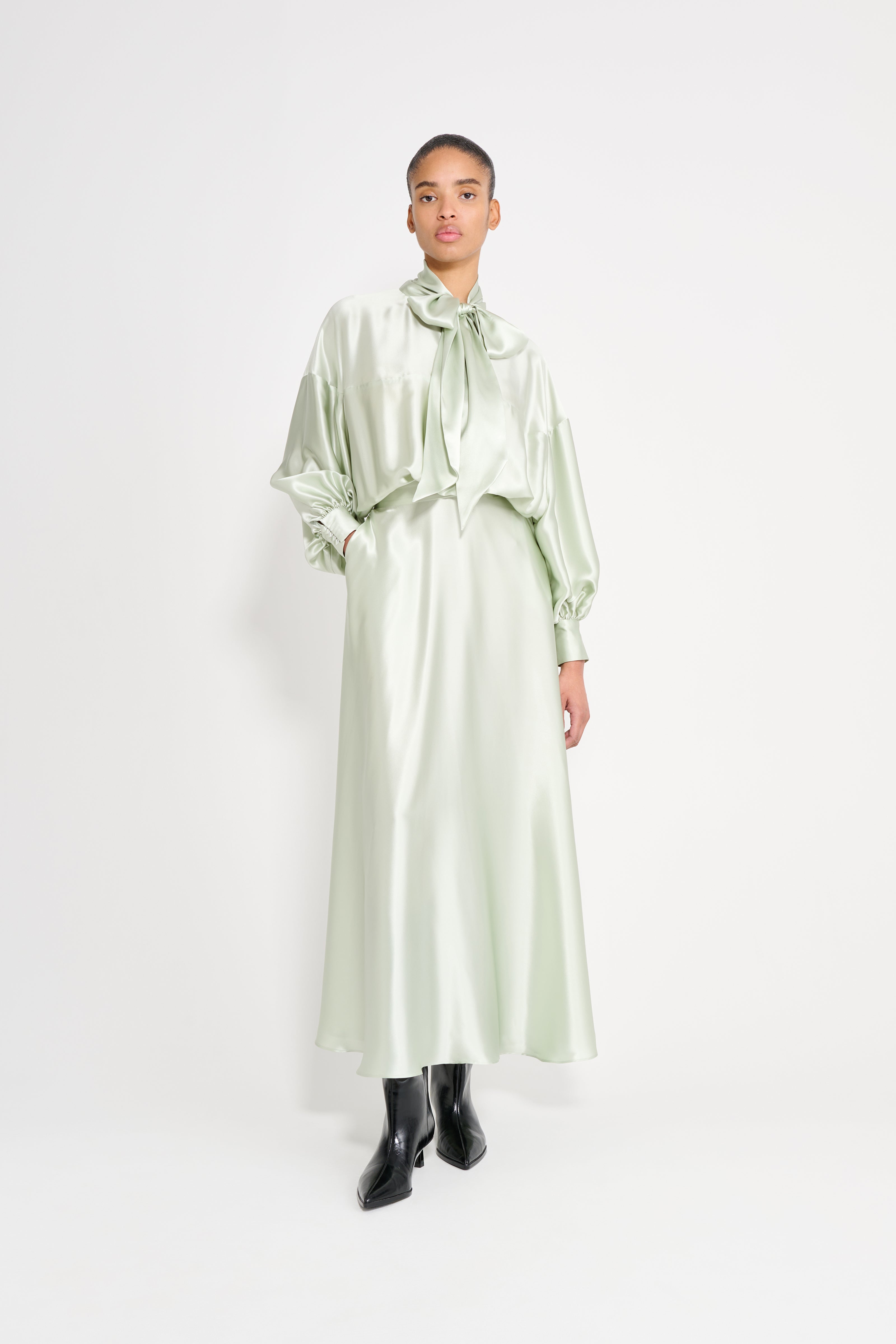 Woman wearing a light green satin dress on a white background