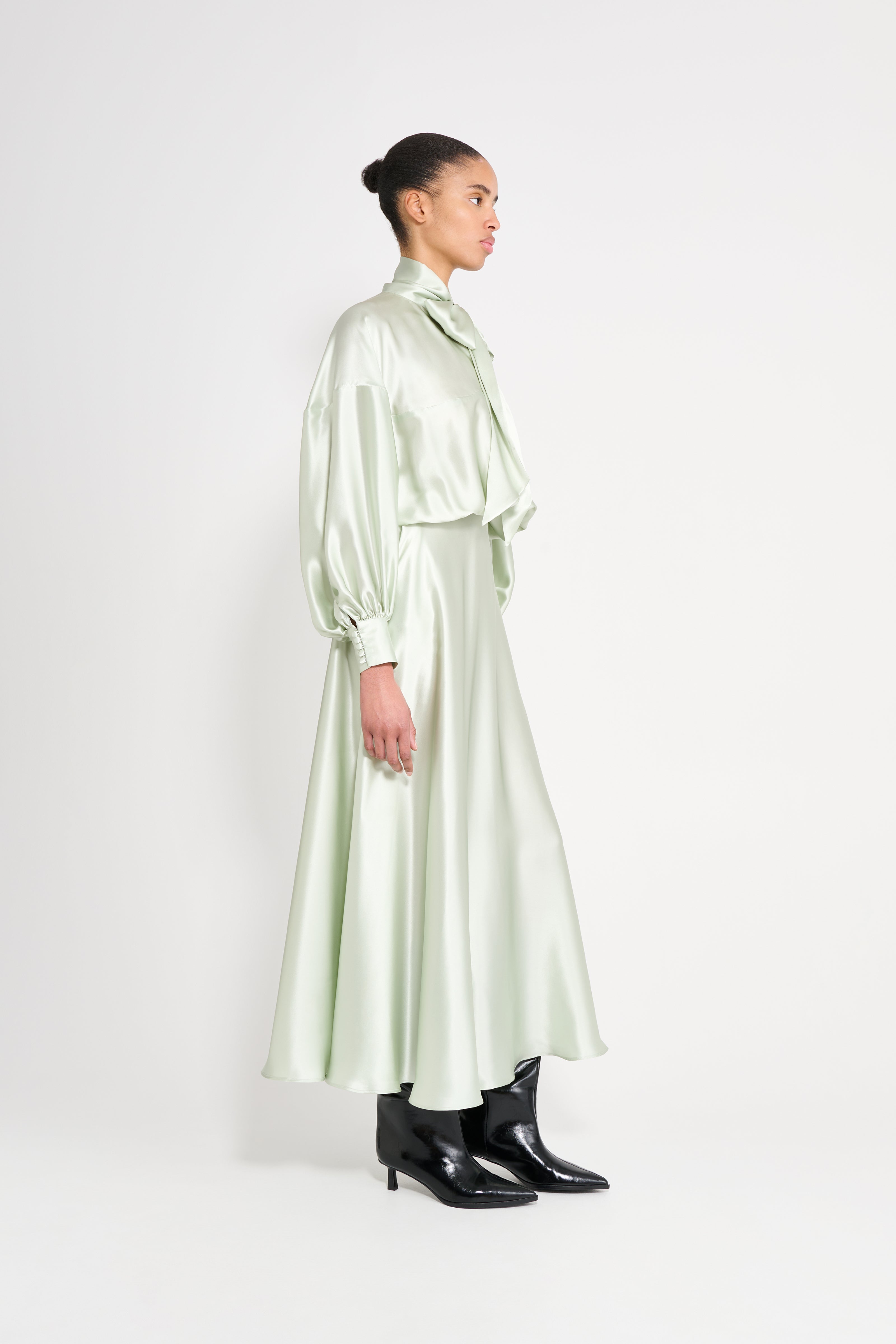 Woman wearing a light green satin outfit on a white background