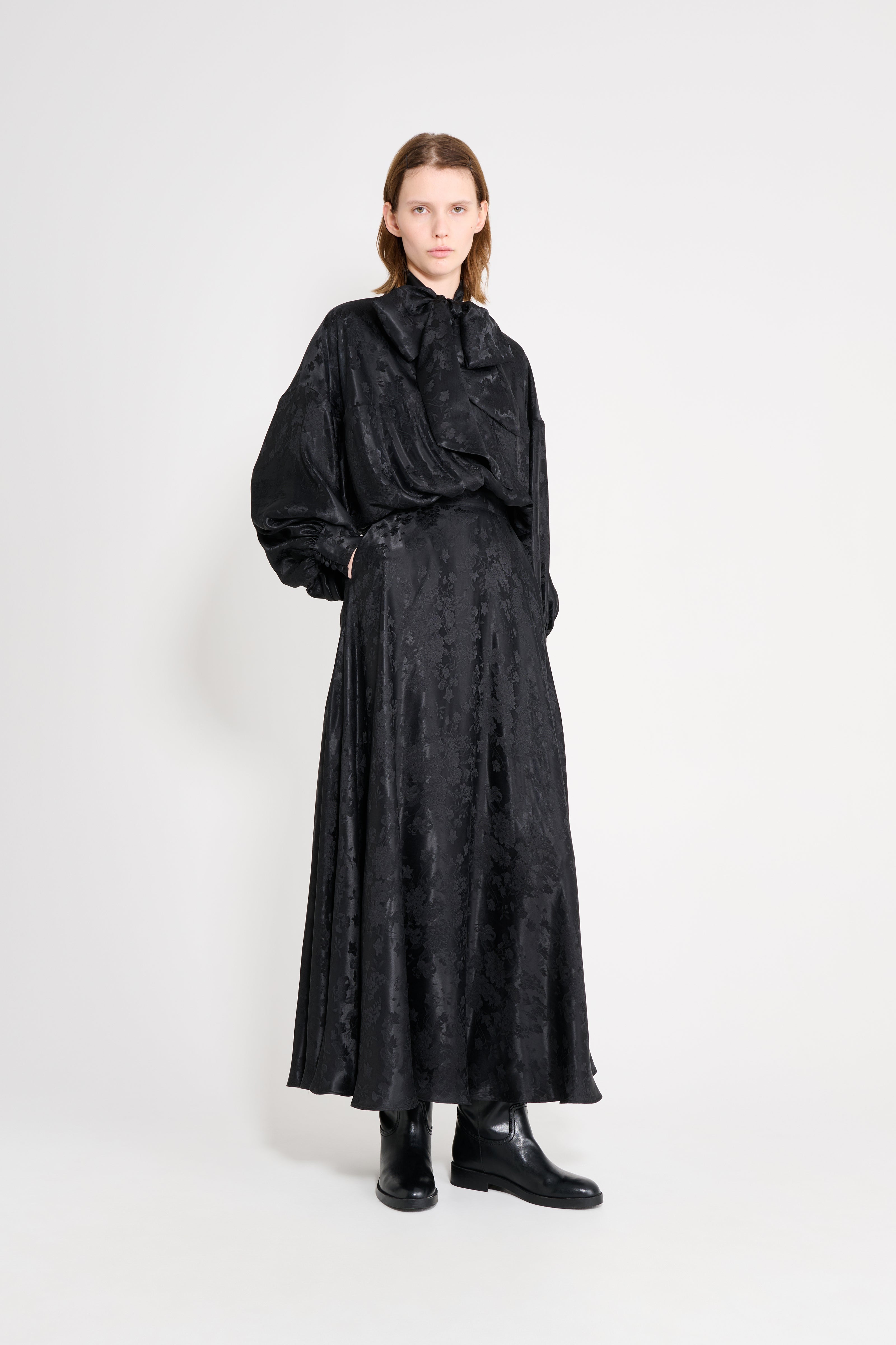 Person wearing a long black coat on a white background