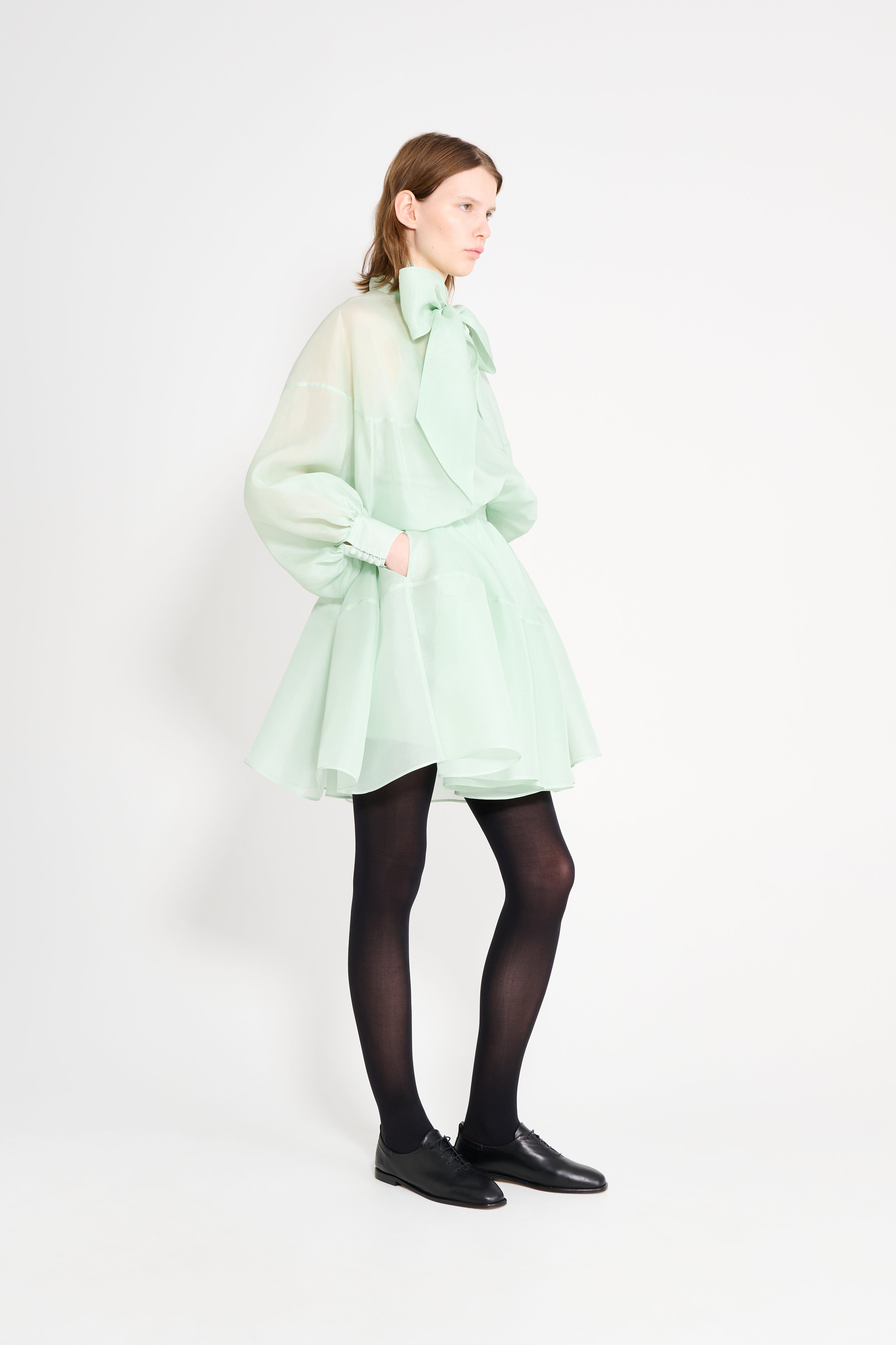 Person wearing a light green coat on a white background