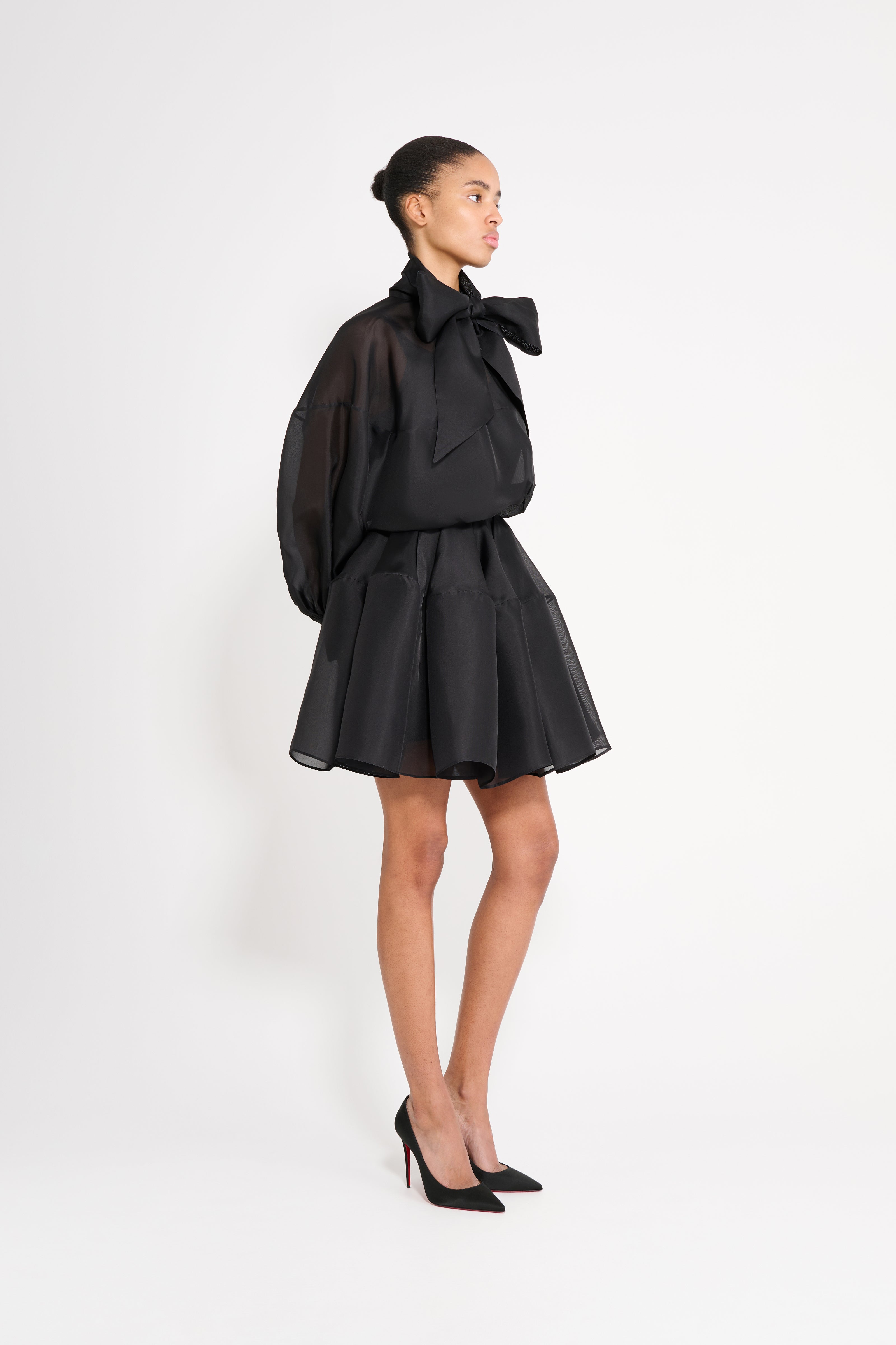 Woman wearing a black outfit with a large bow on a white background