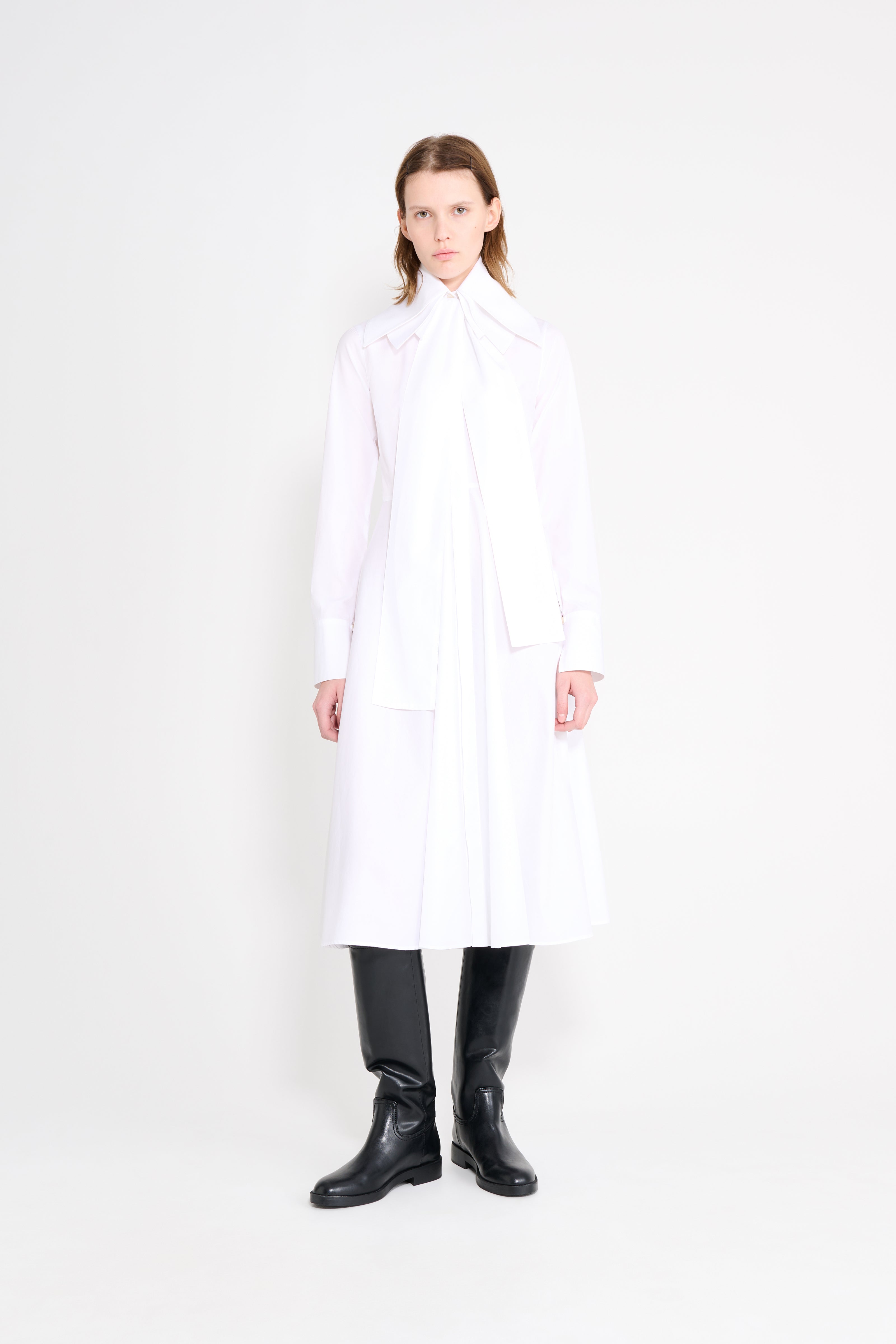 Person wearing a white coat and black boots on a white background
