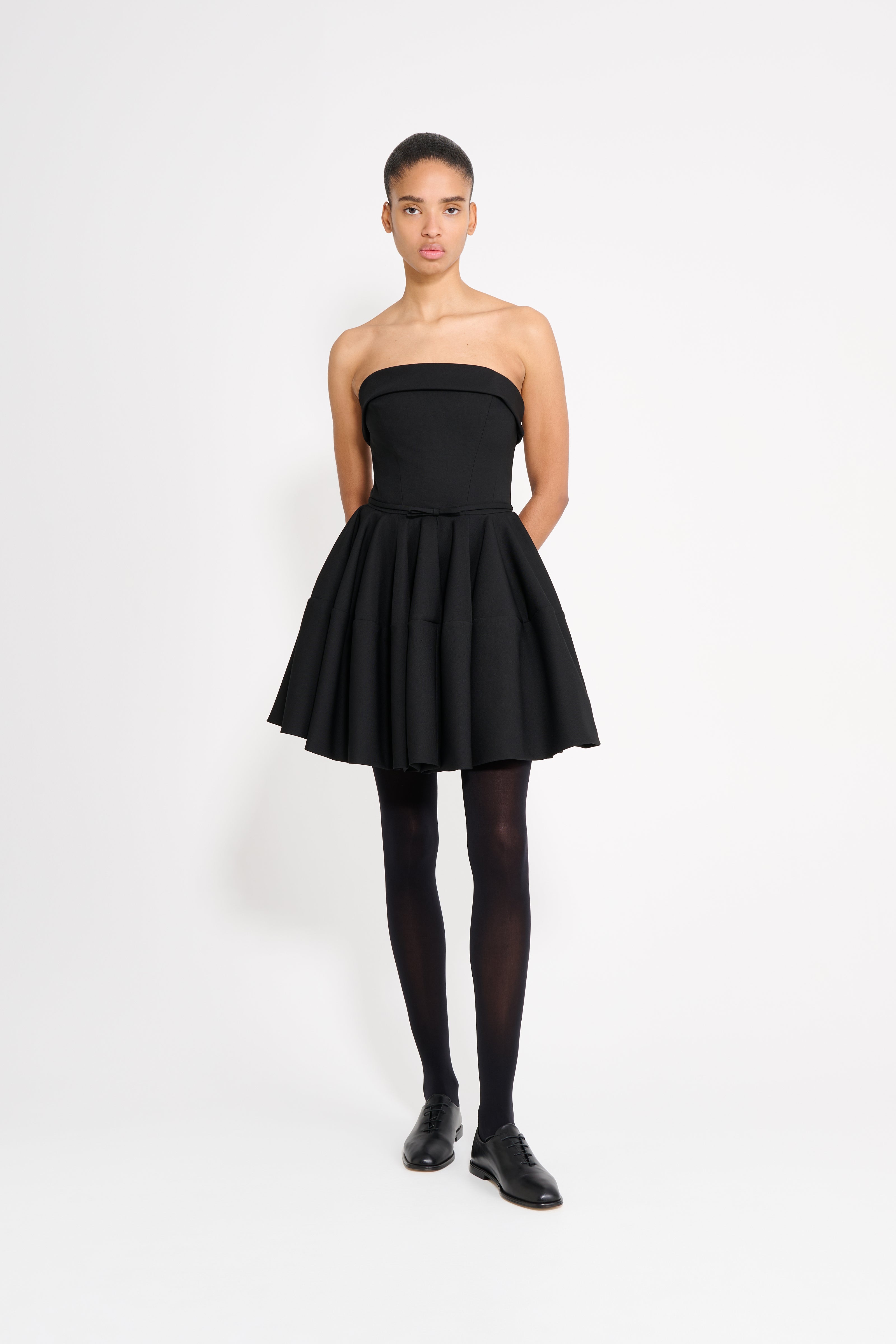 Woman wearing a black strapless dress on a white background
