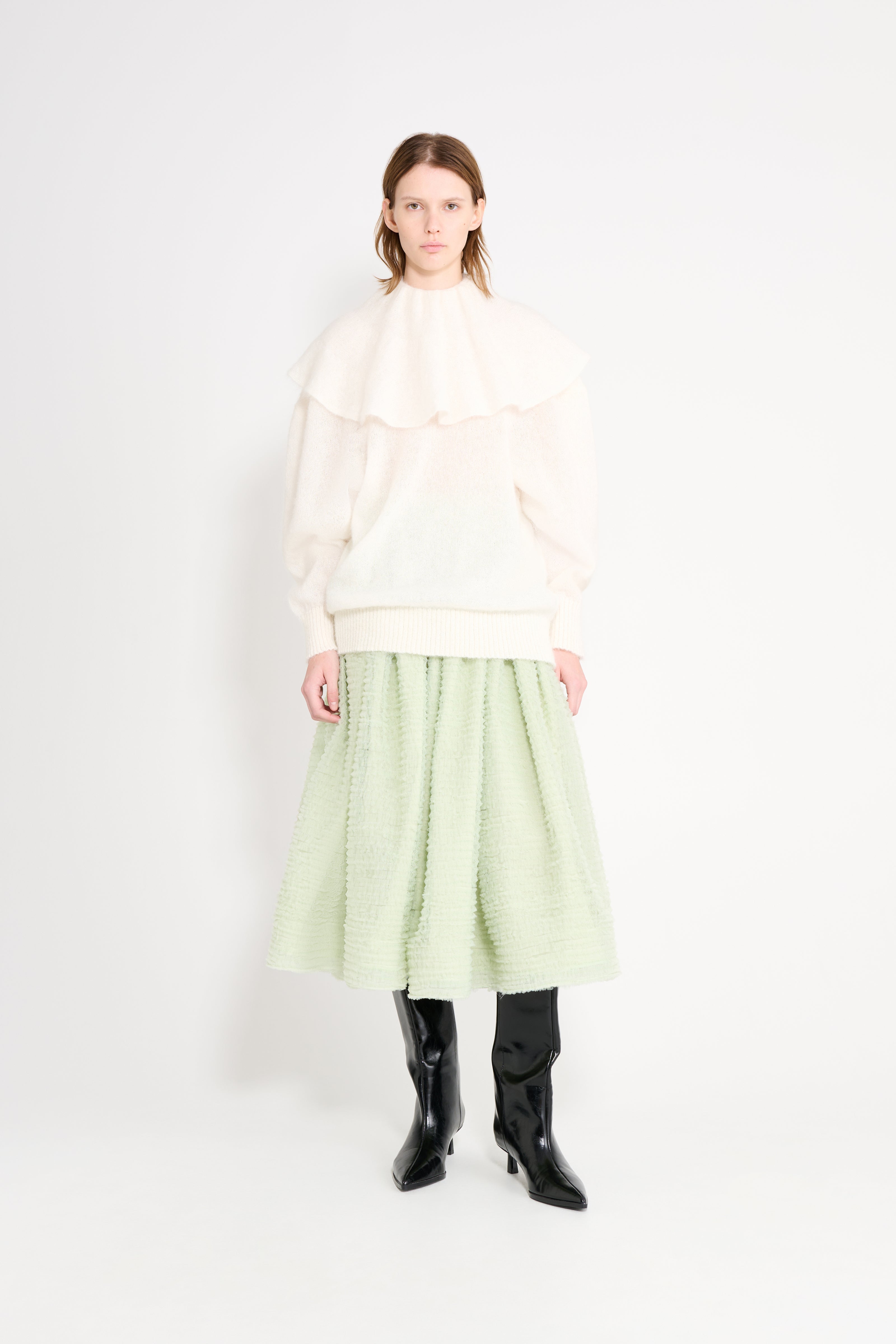 Model wearing a white volant neck sweater with a mint skirt.