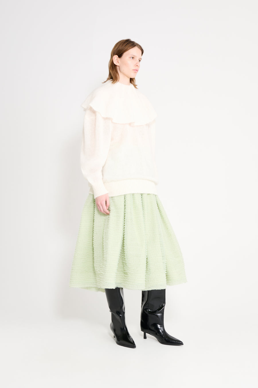 Model wearing a white volant sweater shown from the side.