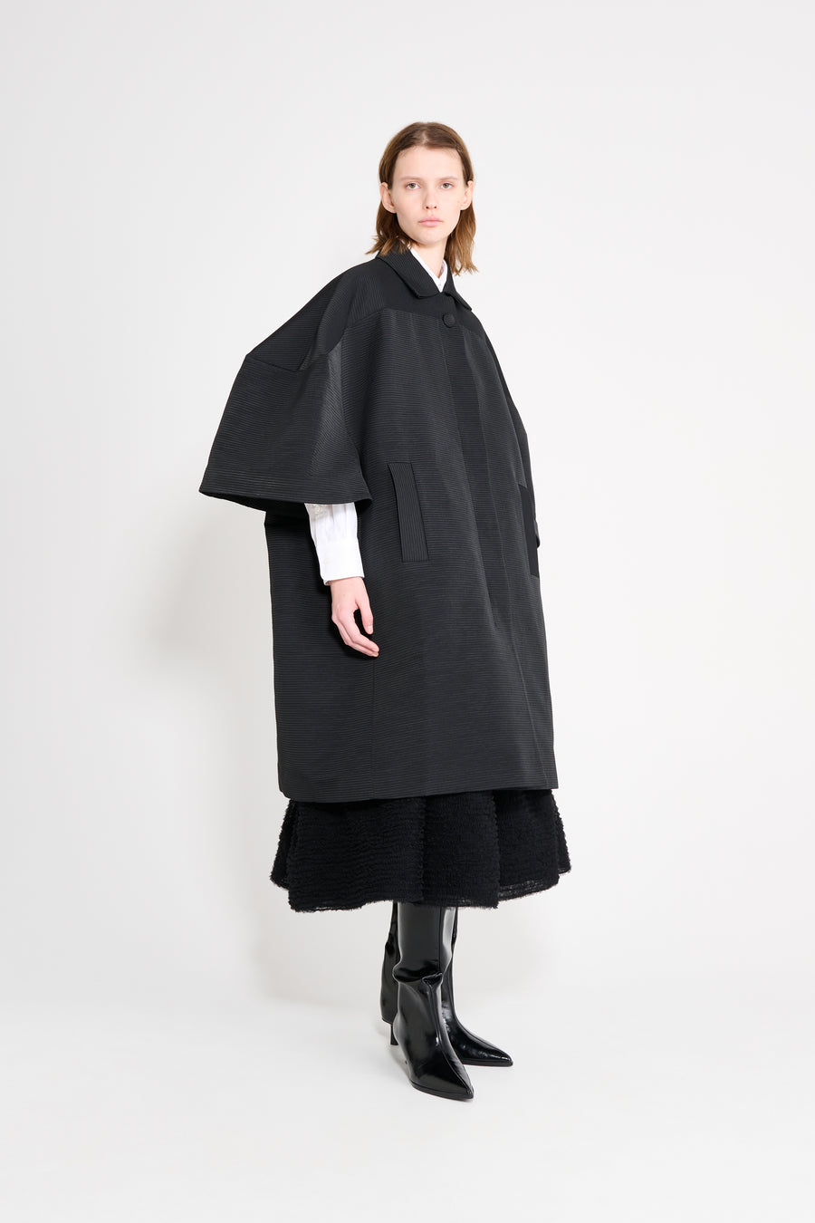 Person wearing a black cape and dress on a white background