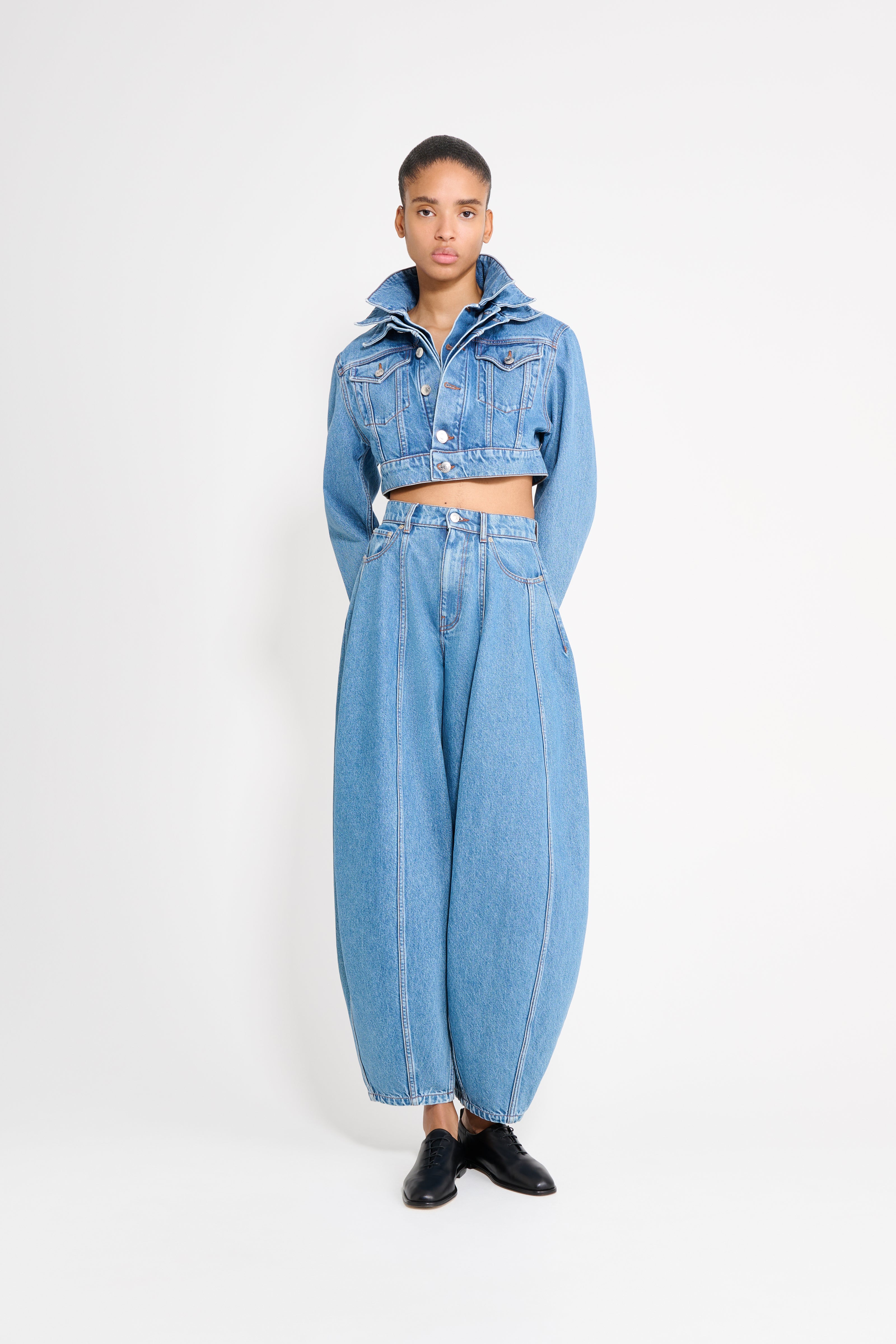 Person wearing a blue denim outfit on a white background