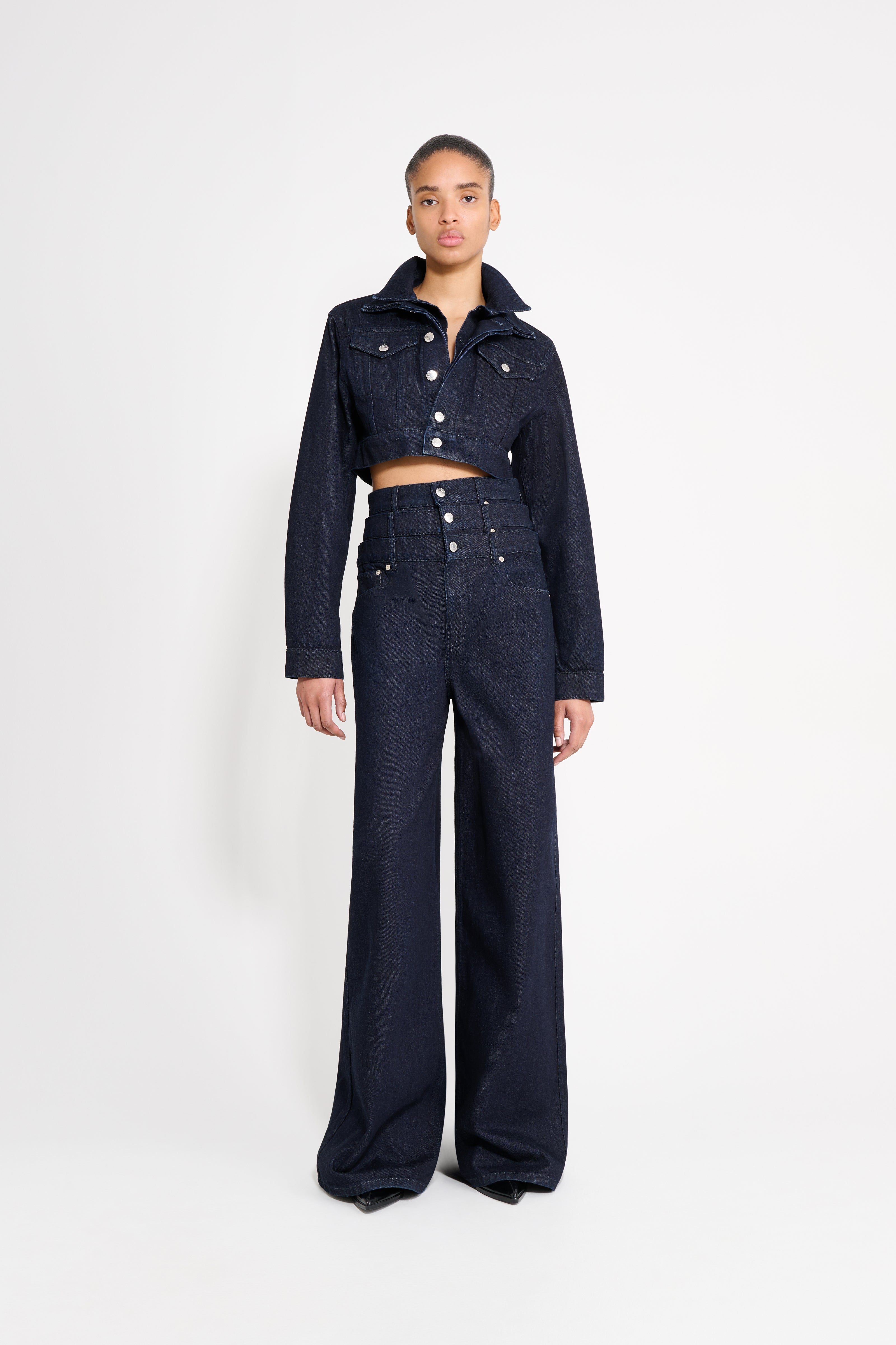 Person wearing a dark denim outfit on a white background