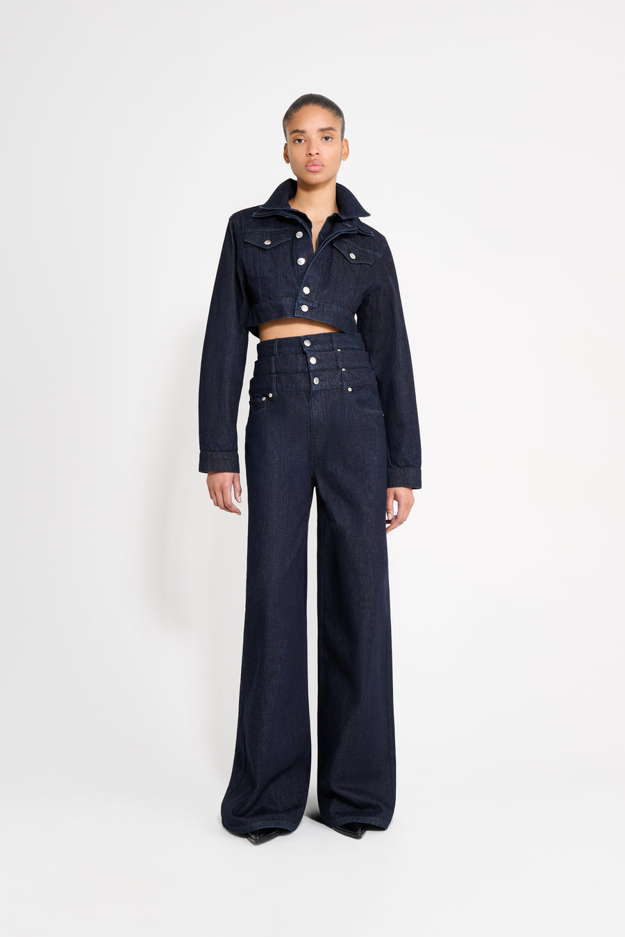 Person wearing a dark denim outfit on a white background