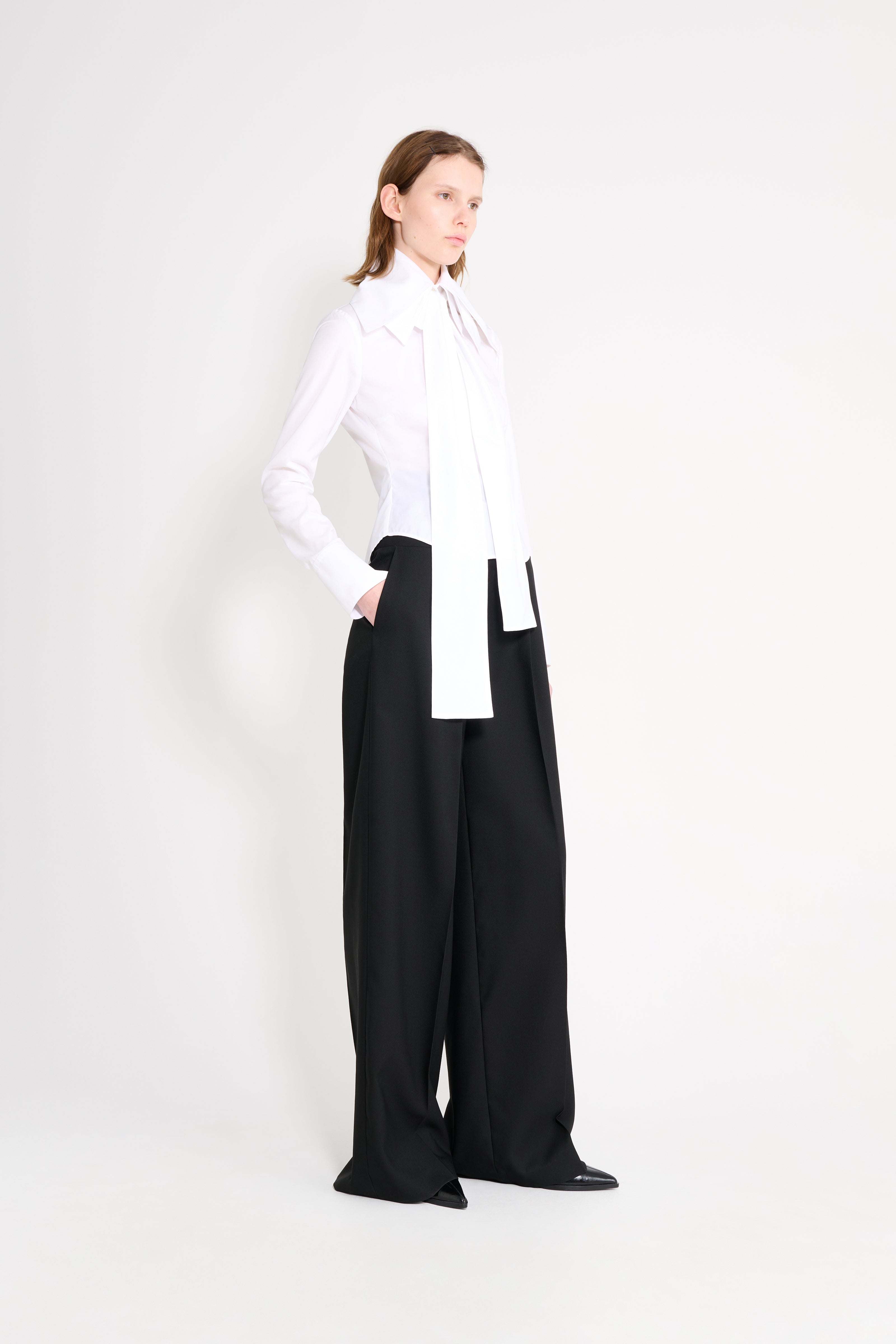 Person wearing a white shirt and black pants on a white background