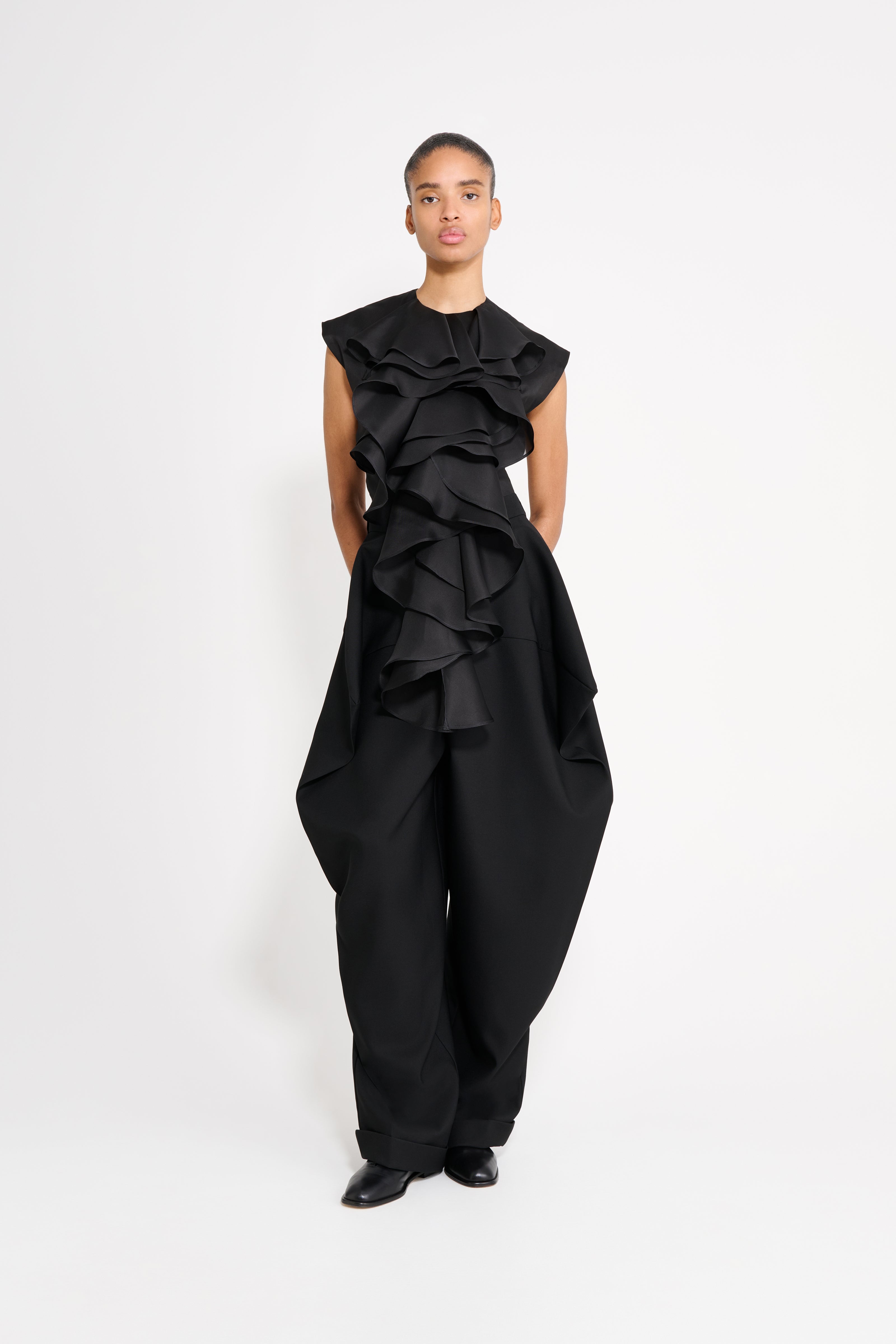 Model wearing a black jabot top on a white background.