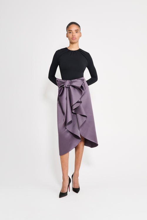 Model wearing a black body with a purple skirt on a white background.