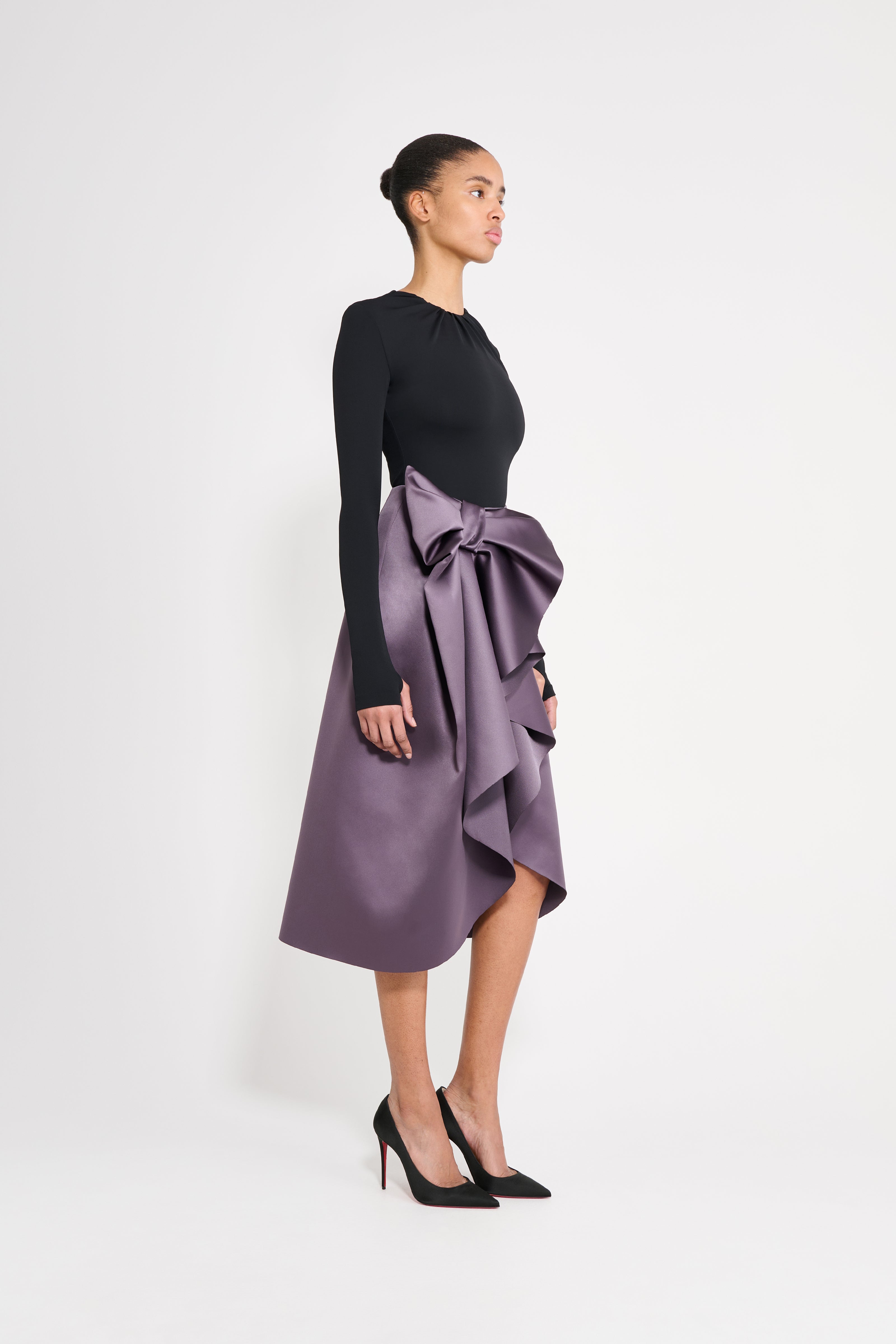 Model wearing a black body with a purple skirt on a white background.