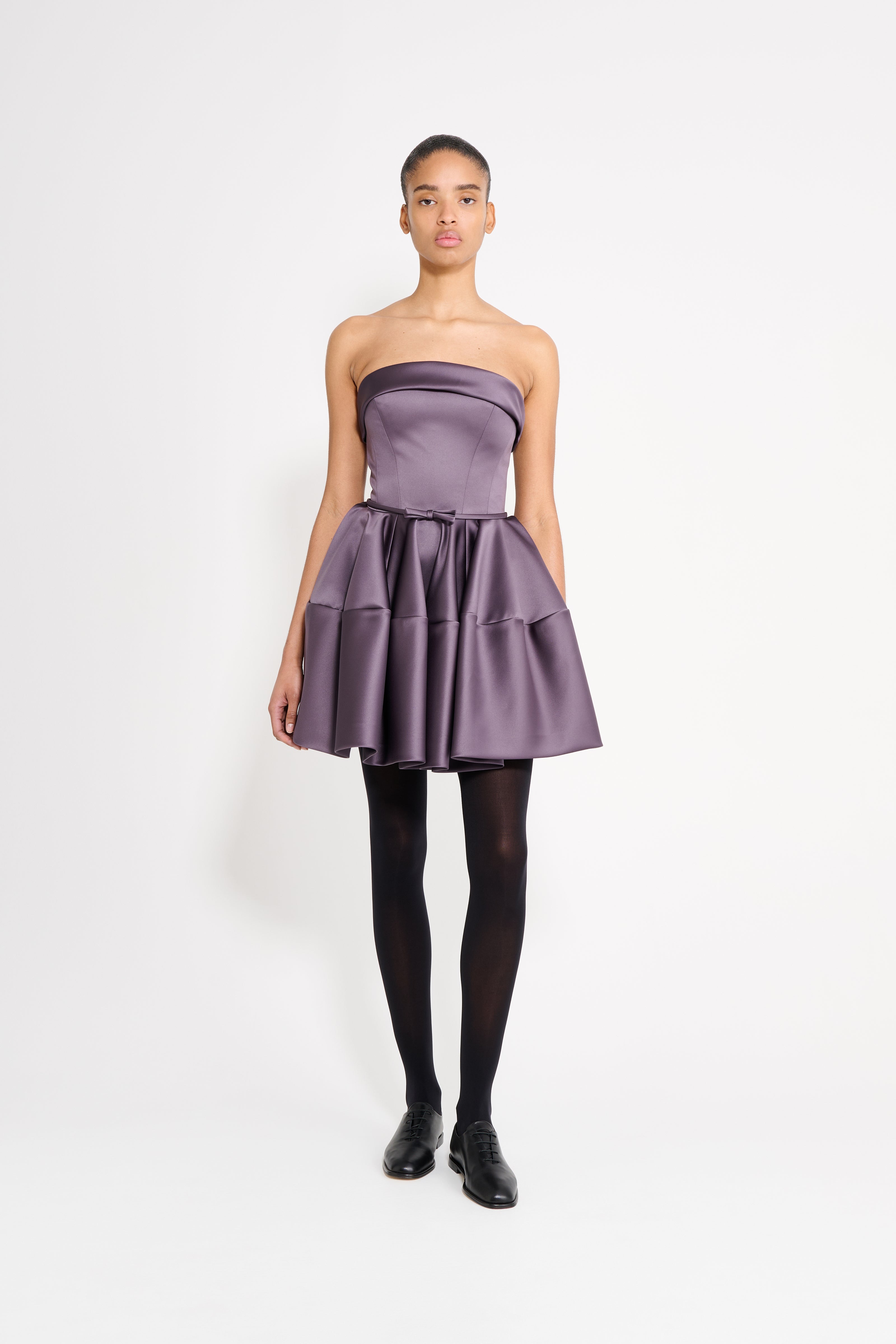 Model wearing a purple mini dress on a white background.