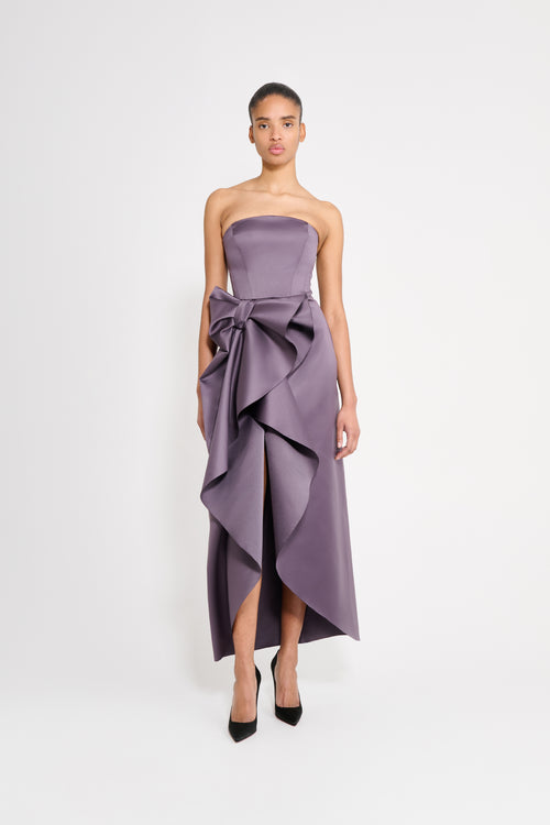 Model wearing a long purple dress on a white background.