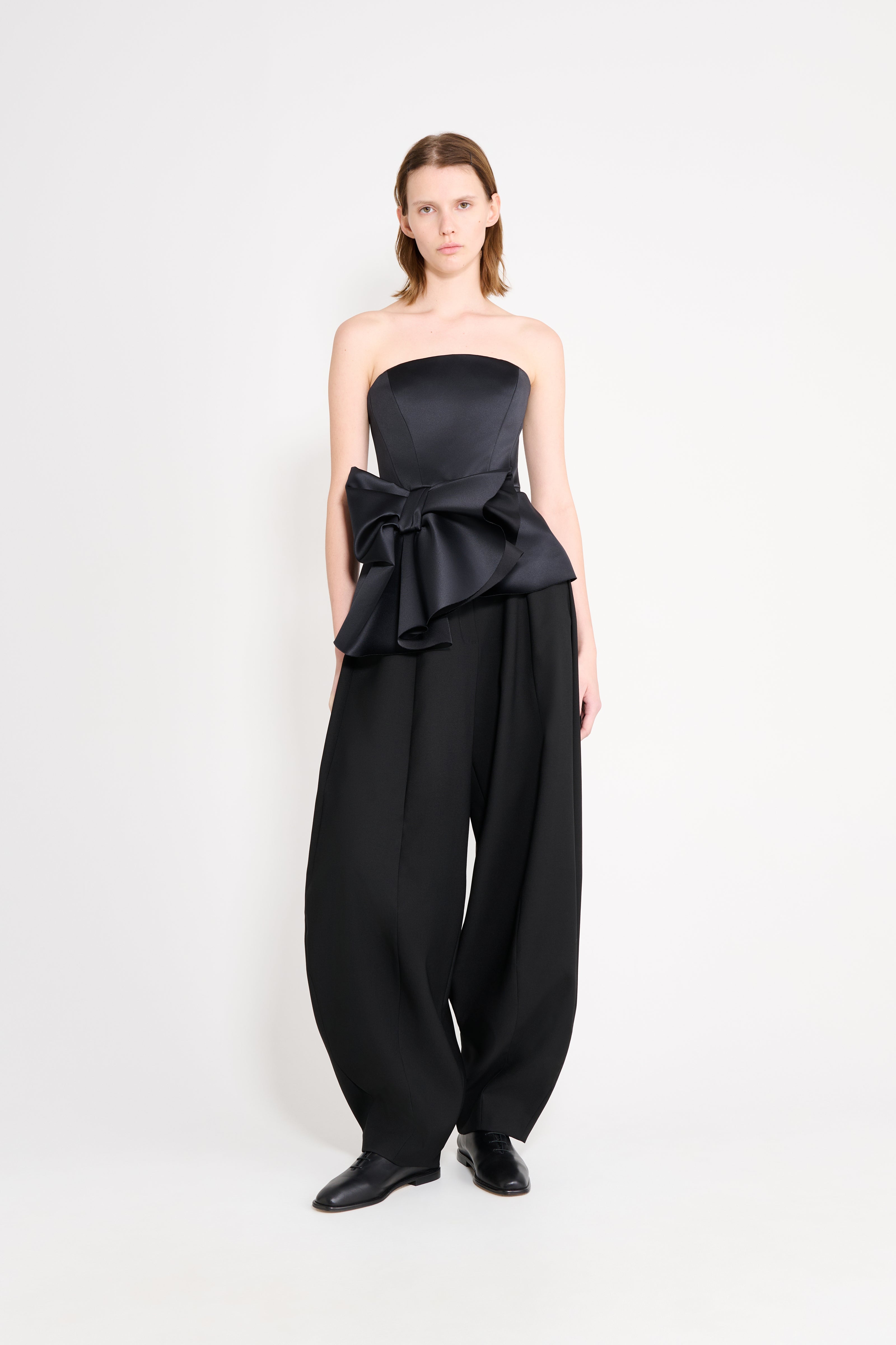 Model wearing a black top with black pants on a white background.