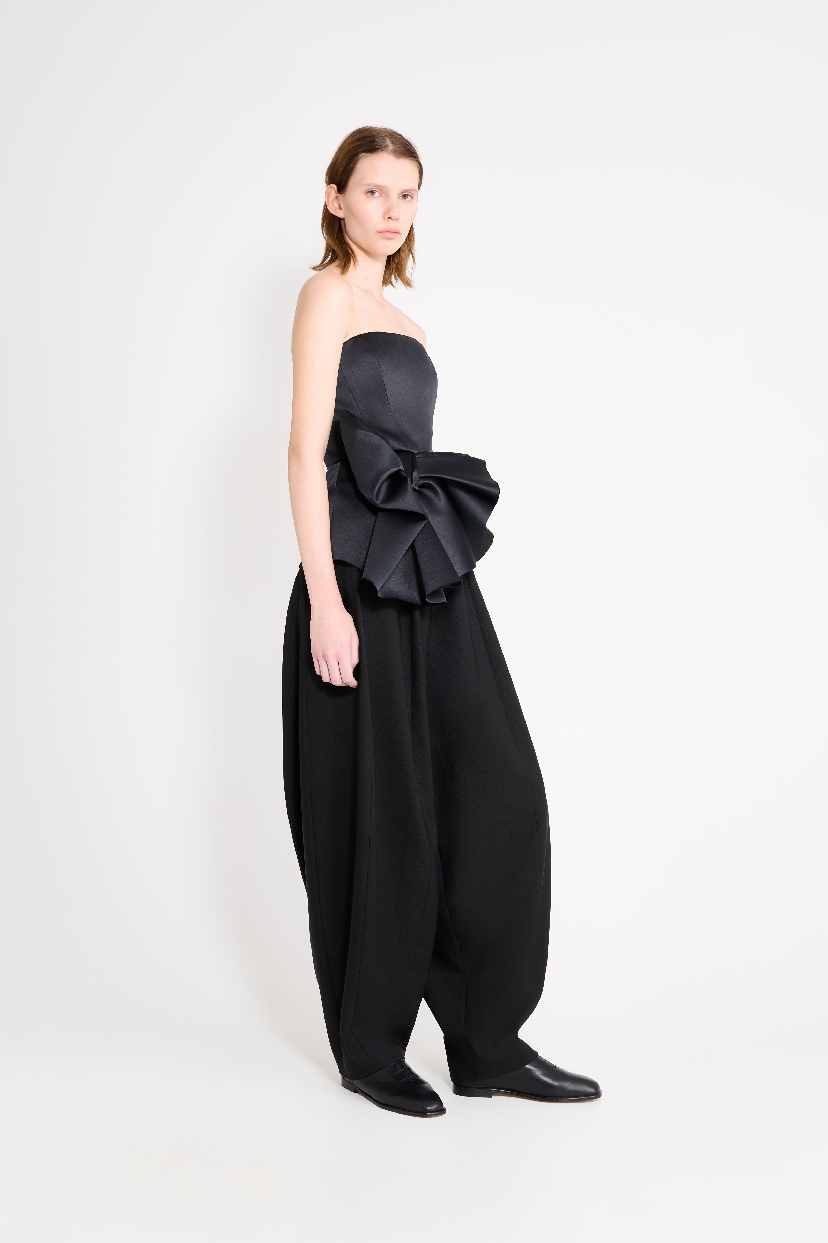 Model wearing a black top with black pants on a white background.