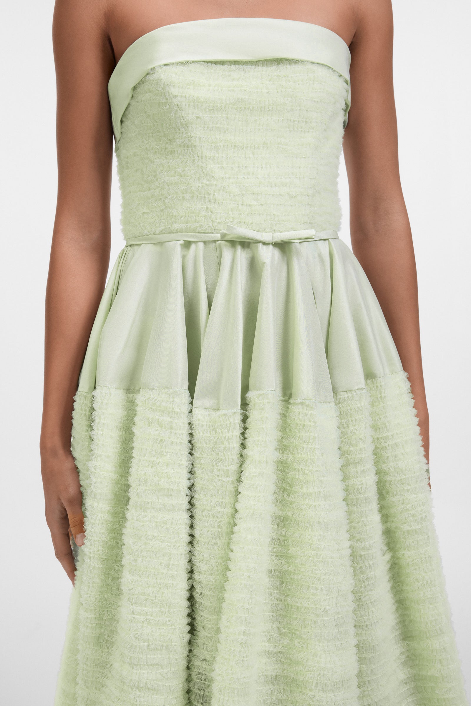 Model wearing a mint green strapless tulle gown on a white background.