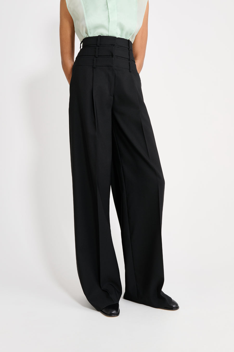 Person wearing black wide-leg pants on a white background