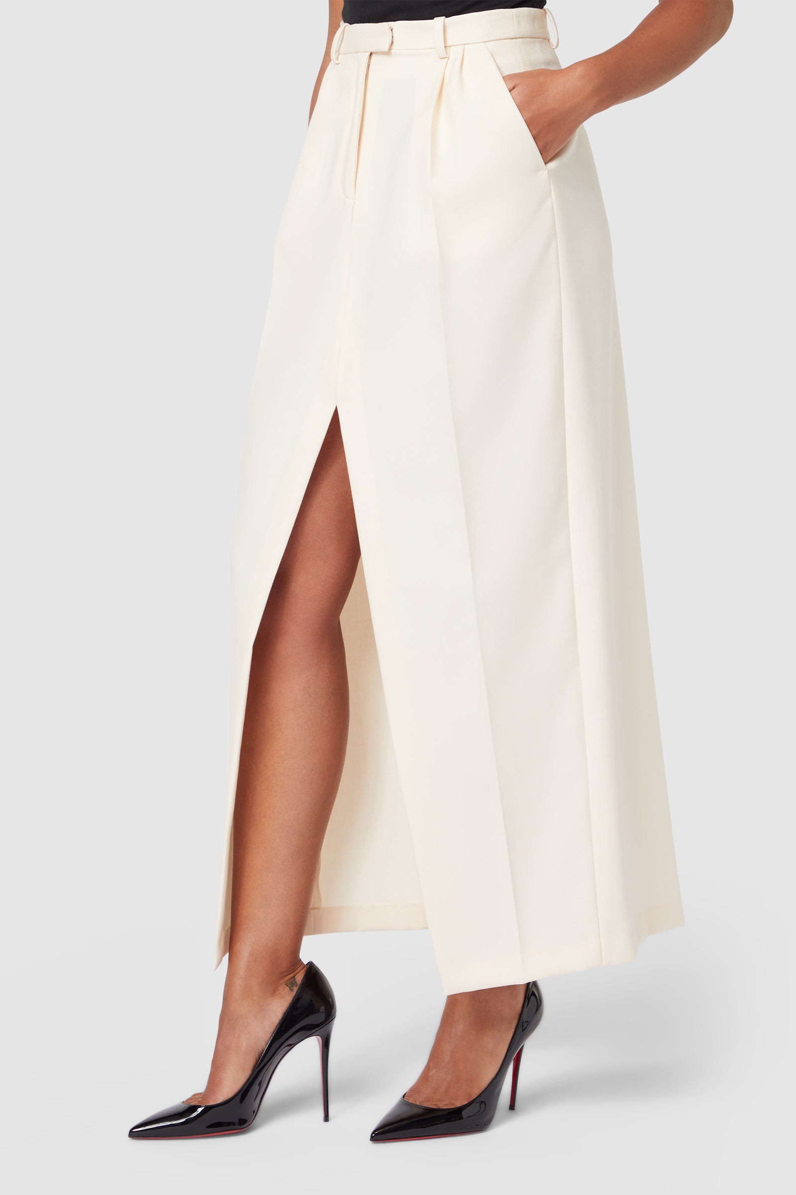 Elegant ivory midi skirt featuring a front slit and high waist design, paired with classic black stiletto heels.