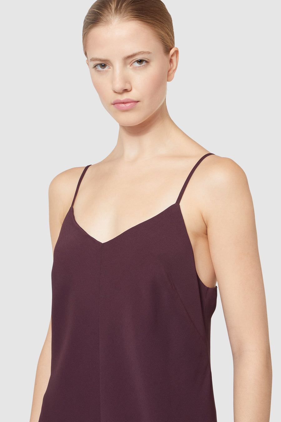 Sleek spaghetti strap dress in deep plum color highlighting minimalistic design and fine tailoring for a chic look.