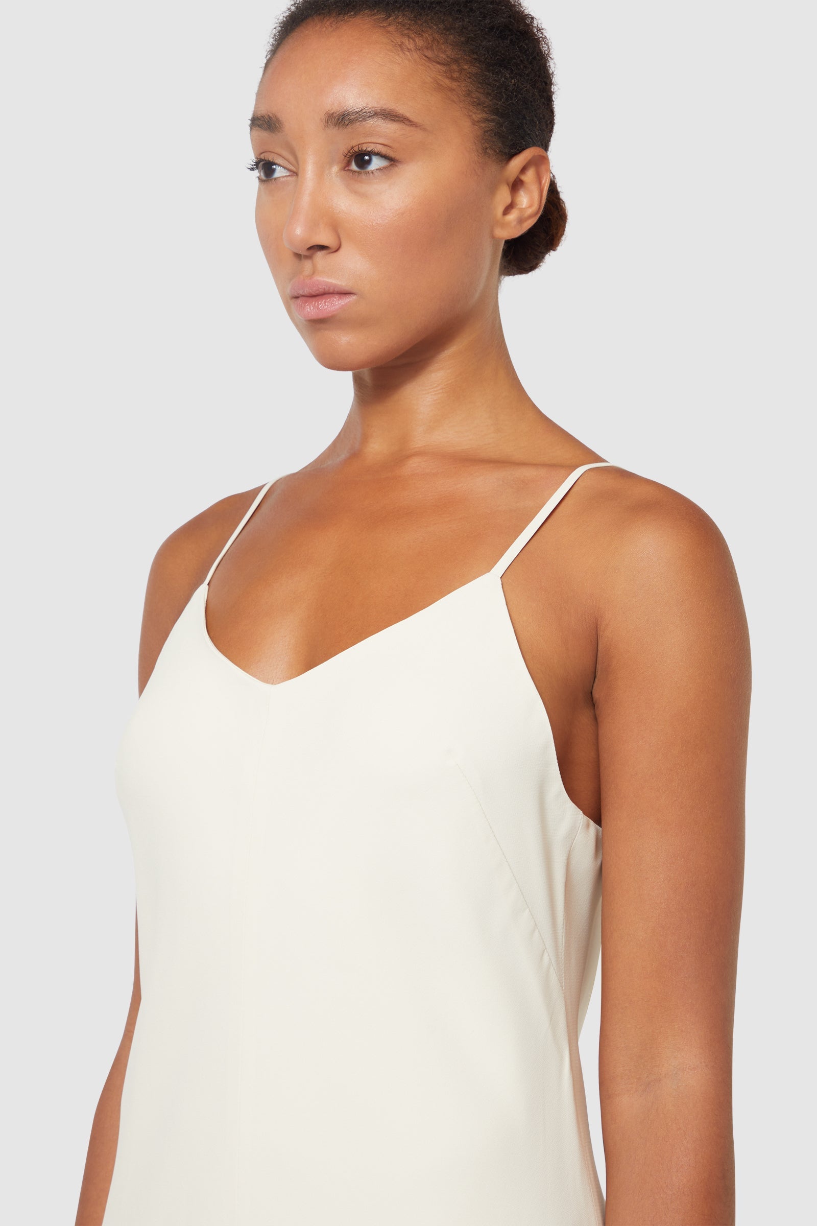 Sleeveless ivory silk slip dress with delicate adjustable spaghetti straps, offering a smooth and elegant silhouette.