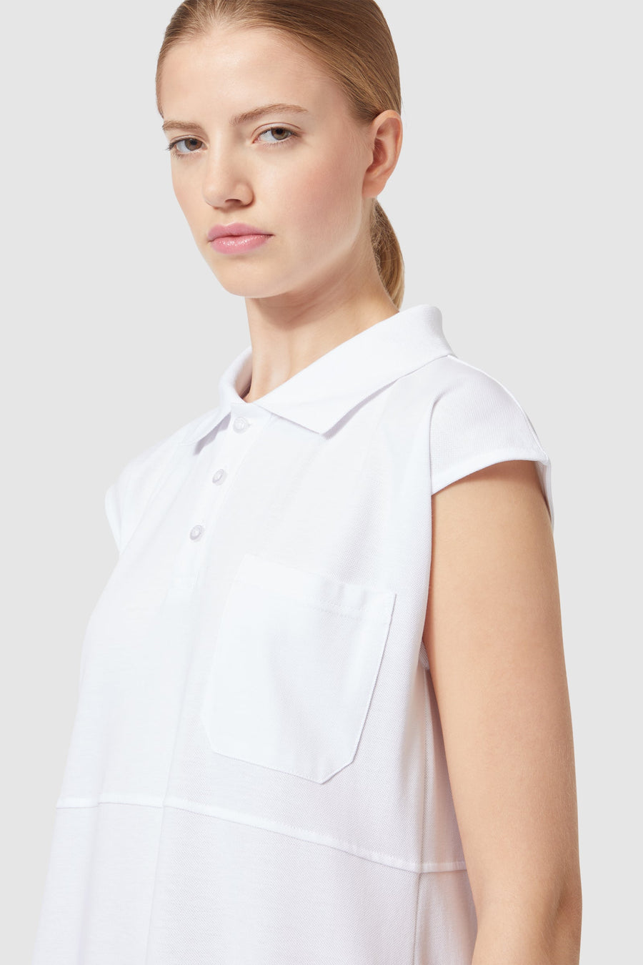 Sleeveless white cotton polo shirt featuring a single chest pocket and a classic button-down collar, elegantly tailored fit.