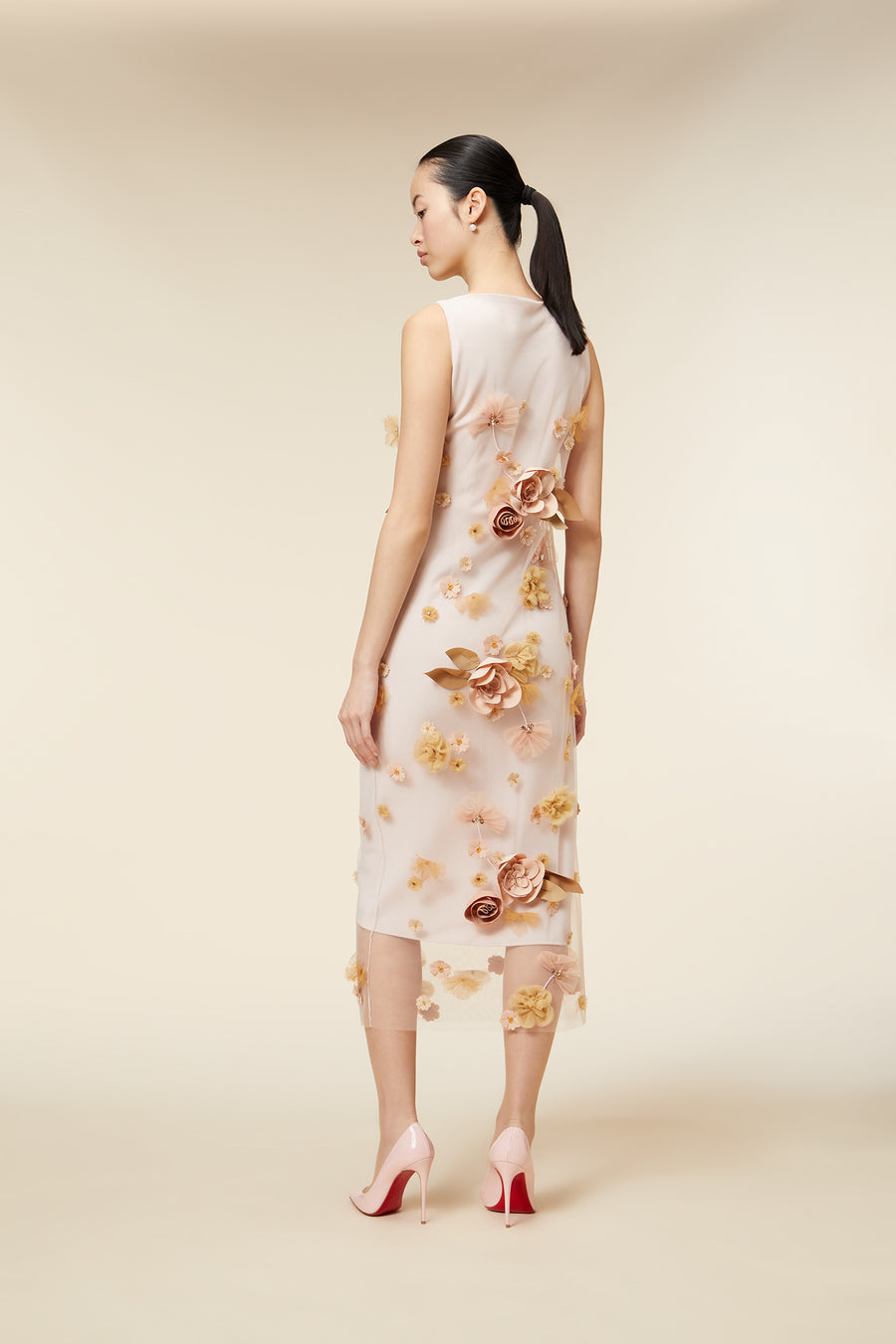 Elegant sleeveless dress with floral appliqué detailing in soft pastel tones, featuring a sheer overlay and classic silhouette.