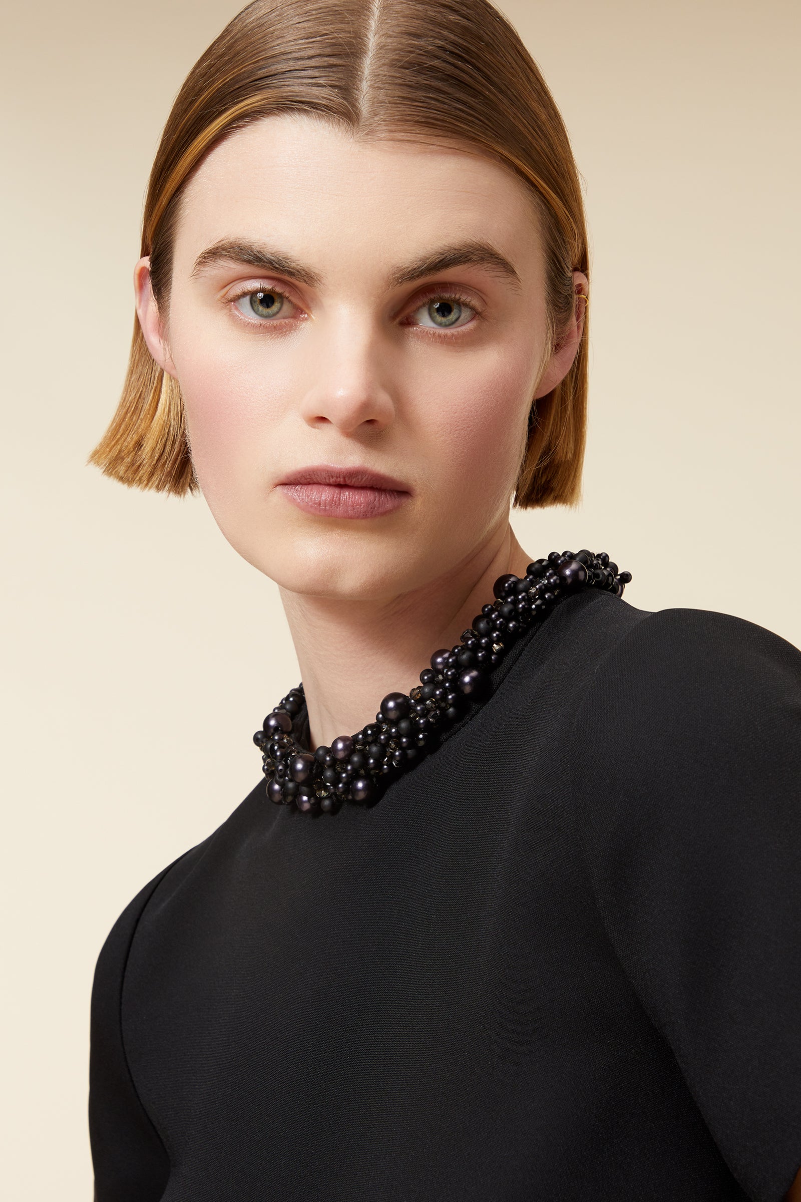 Elegant black A-line dress with beaded collar and pockets, perfectly paired with sheer black tights and simple pointed heels.