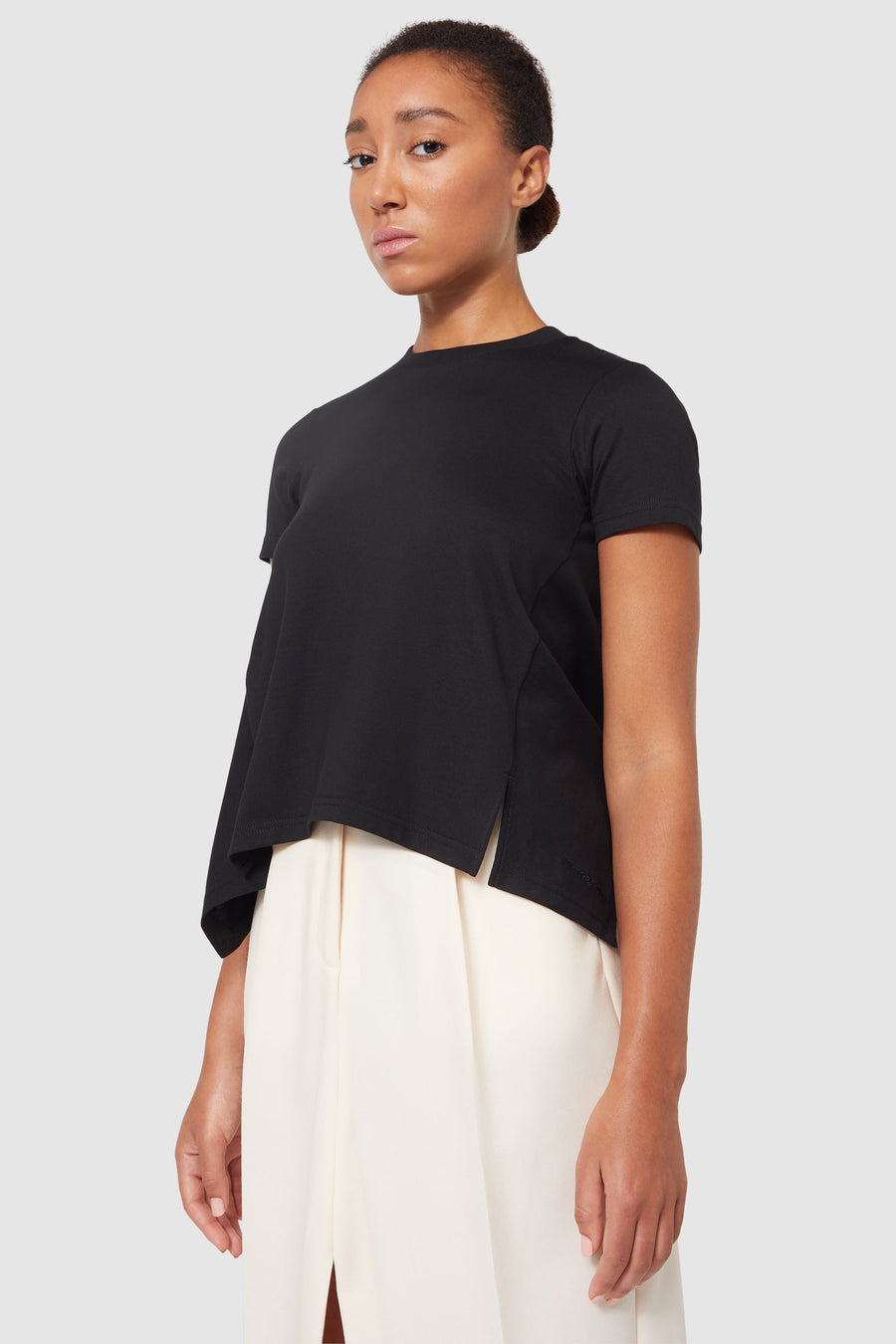 Black asymmetrical short-sleeve top paired with a flowing cream skirt, creating a stylish modern contrast.