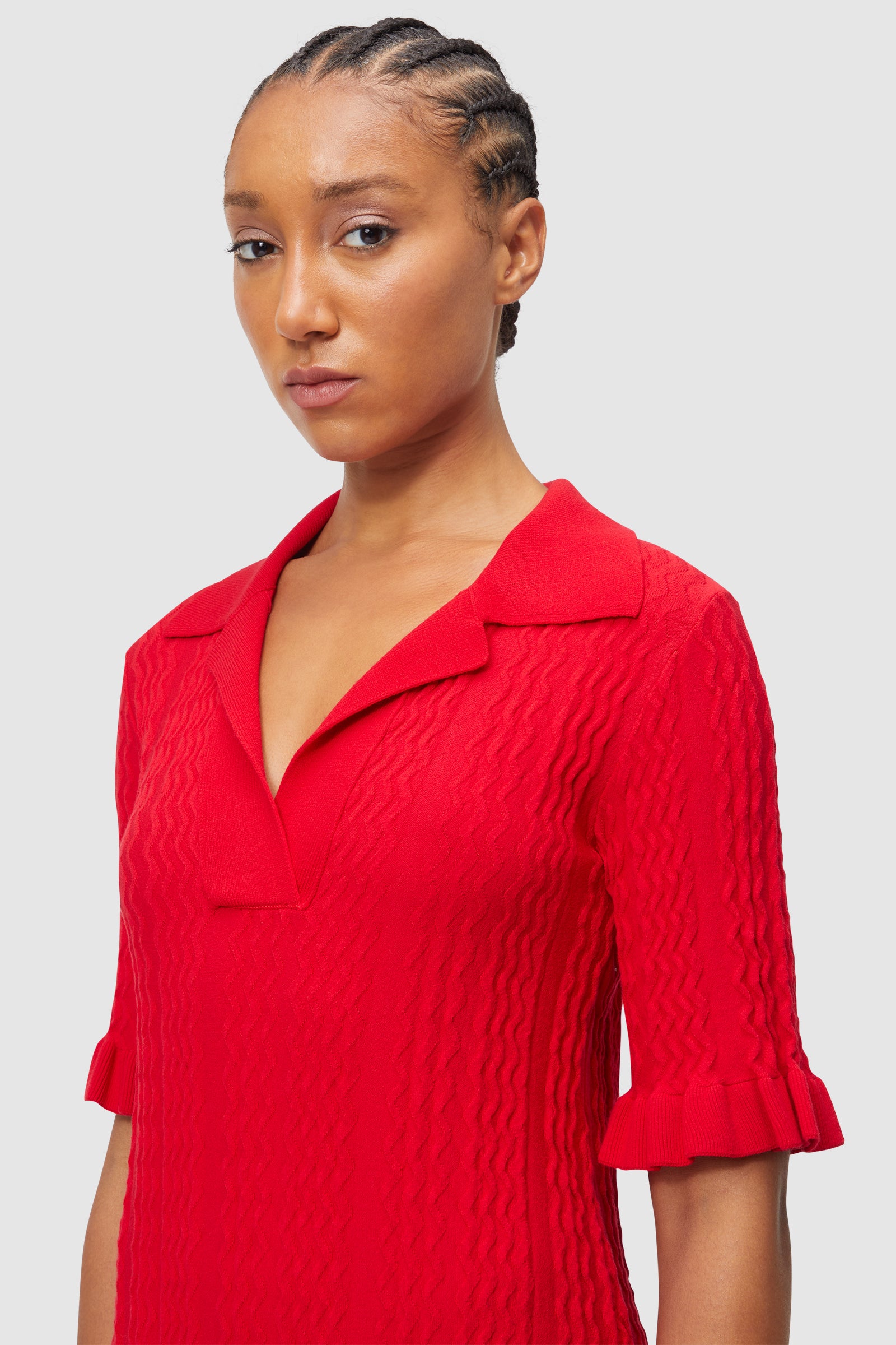 Elegant textured red knit dress with a collared V-neckline and ruffled half sleeves, highlighting stylish design details.