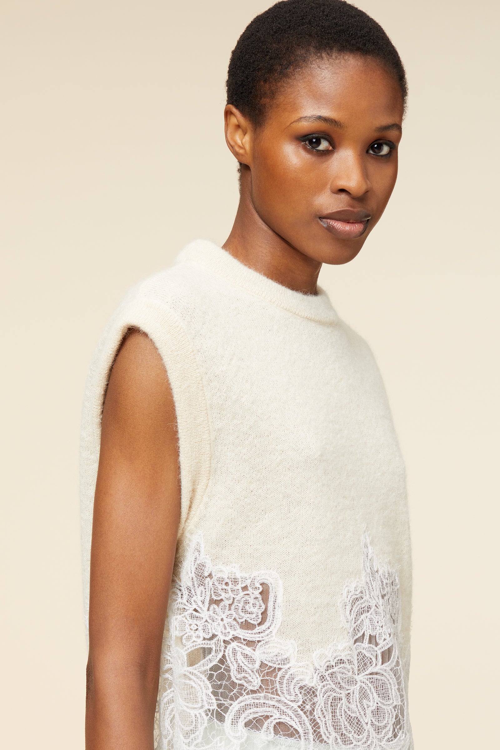 Sleeveless wool top in cream, featuring intricate white lace floral details, exuding a soft and elegant style.