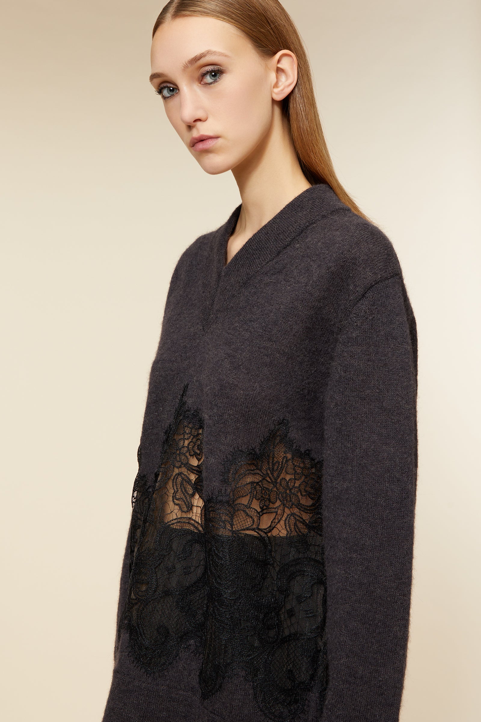 Cozy dark gray knit sweater adorned with ornate black lace detailing at the waist, creating an elegant contrast.