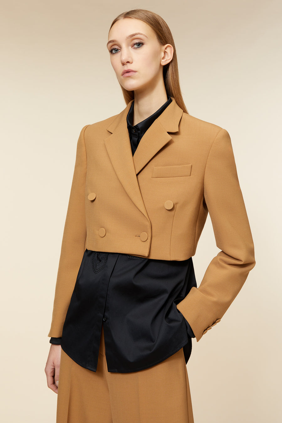 Tailored camel double-breasted blazer with structured shoulders and sleek black underlayer, adding contrast and sophistication.